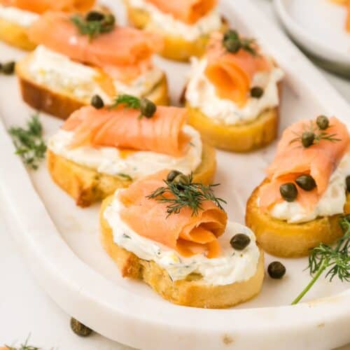 Smoked Salmon Crostini on a serving platter garnished with fresh dill and capers.
