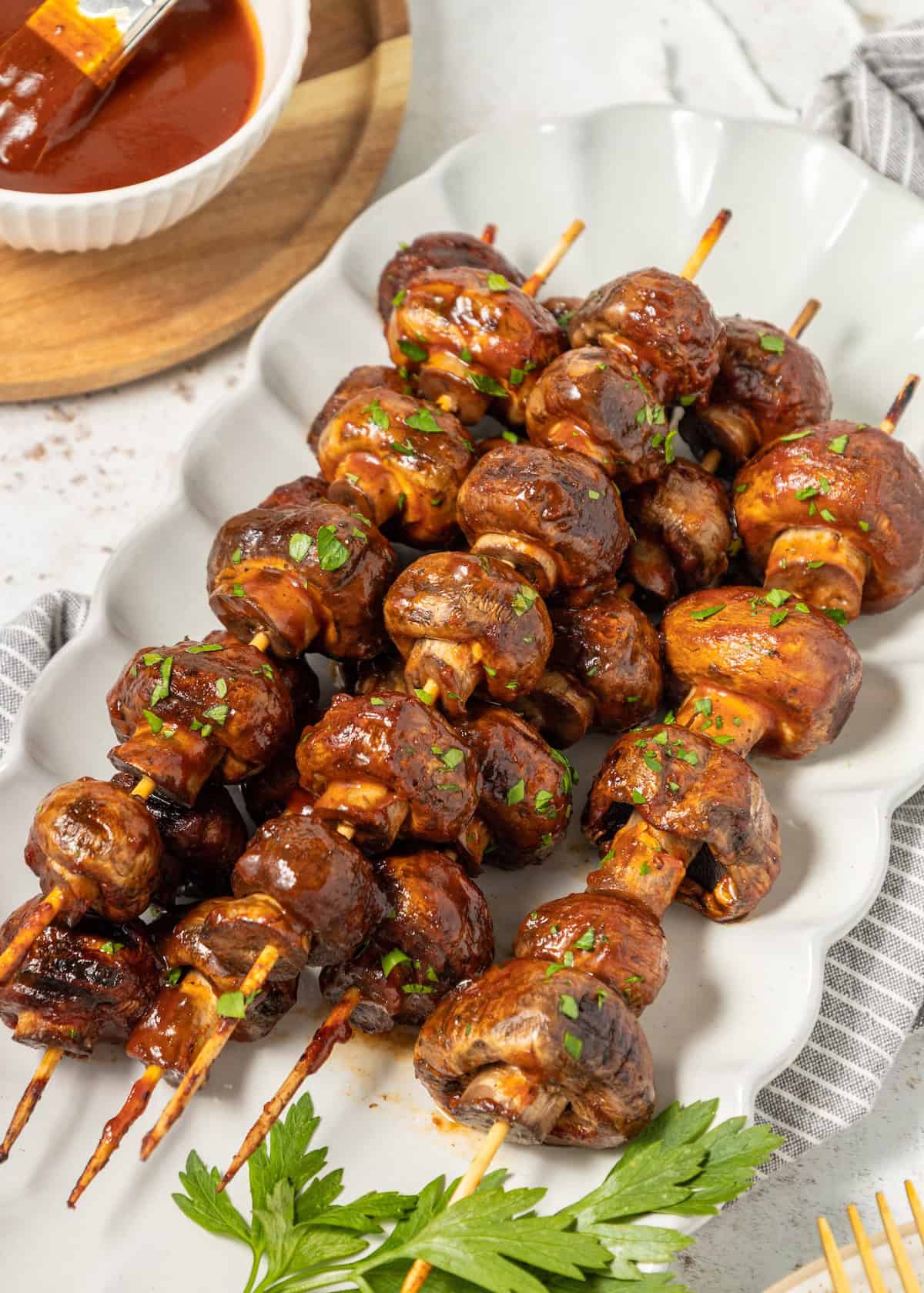 BBQ Mushrooms skewers with barbecue sauce, garnished with chopped herbs on a white plate.
