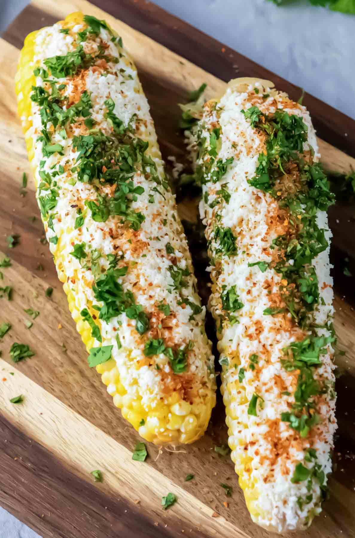 Two ears of Mexican street corn, a classic from easy Mexican recipes, topped with cheese and chili.