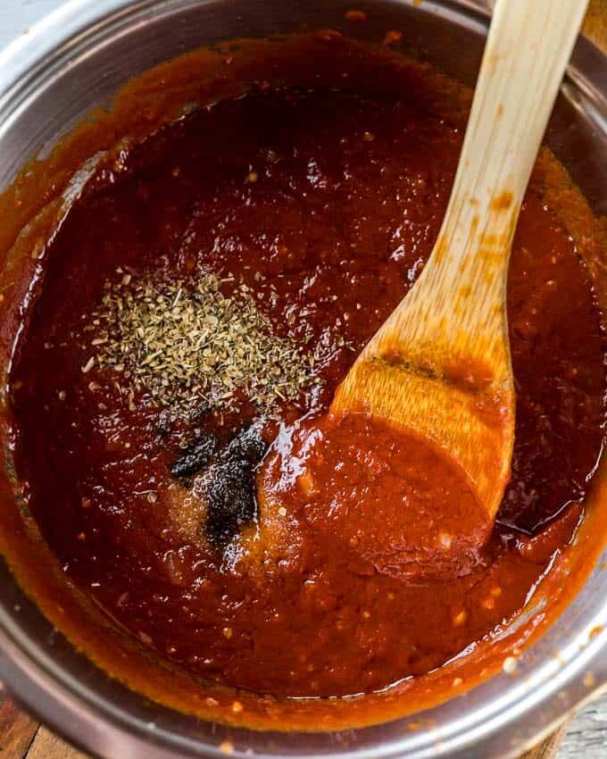 A top shot of a pot with cooking homemade ketchup and wooden spoon.