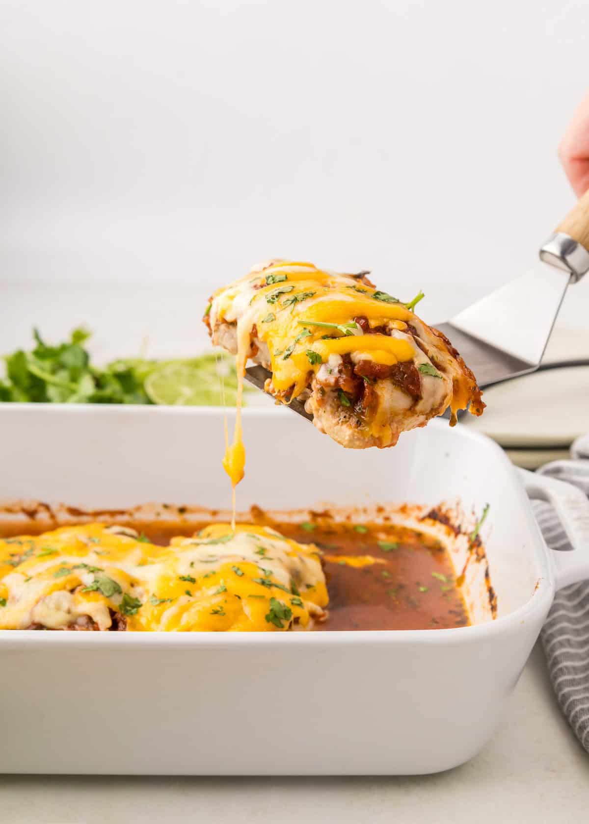 salsa chicken being removed from baking dish