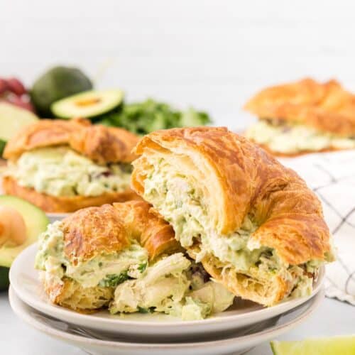 Creamy chicken salad croissant sandwich with fresh lettuce and avocado, served on a white plate, perfect for lunch or light dinner, featuring flaky croissants and healthy ingredients.