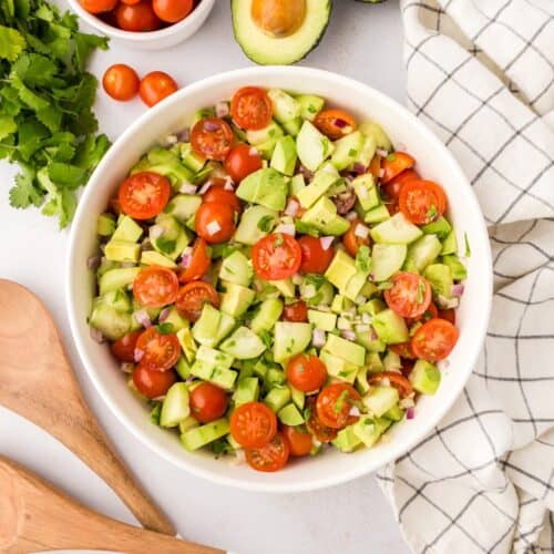 avocado tomato cucumber salad in a white bowl