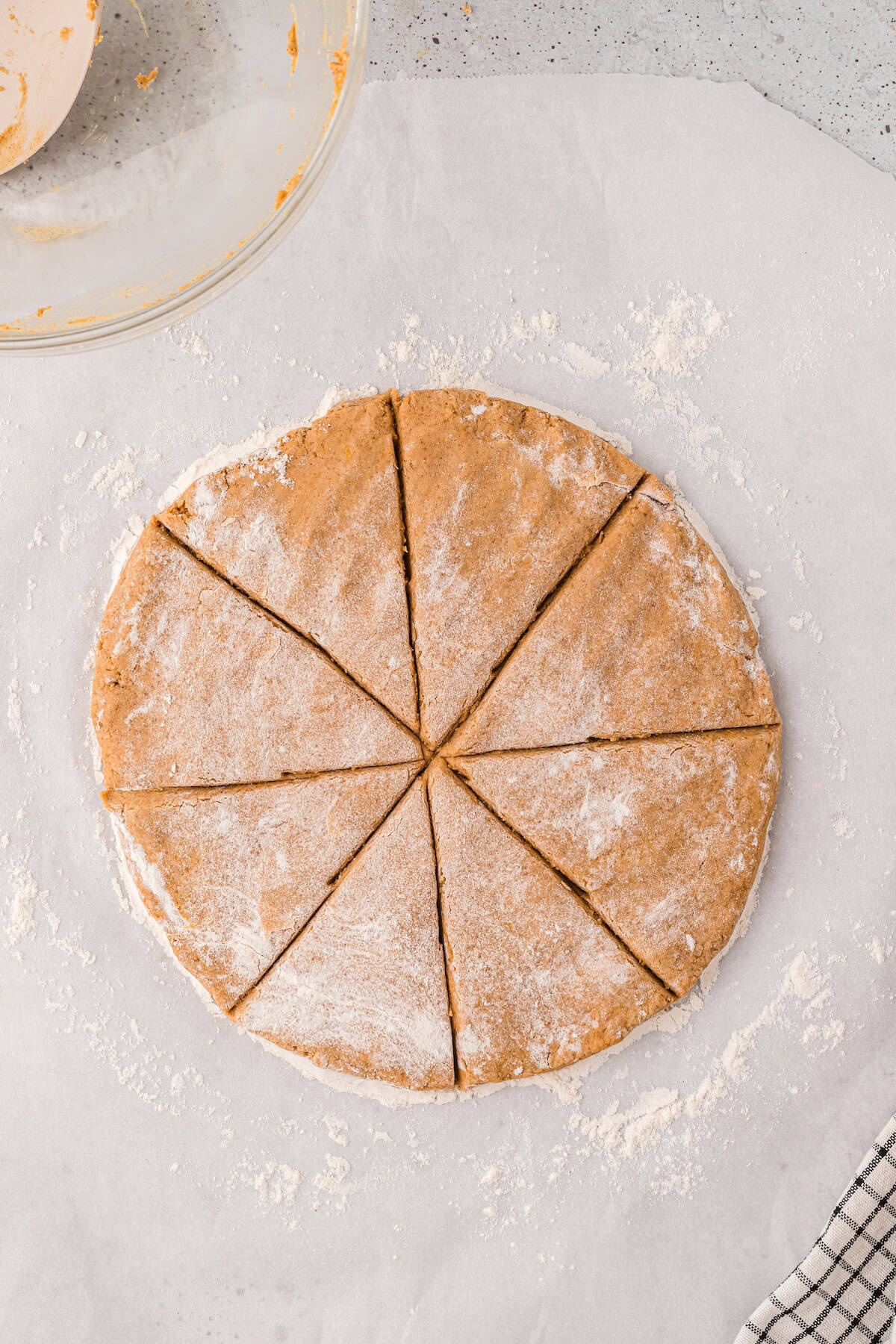 Gluten-Free Pumpkin Scones dough cut into eight wedges on floured parchment, ready for baking.