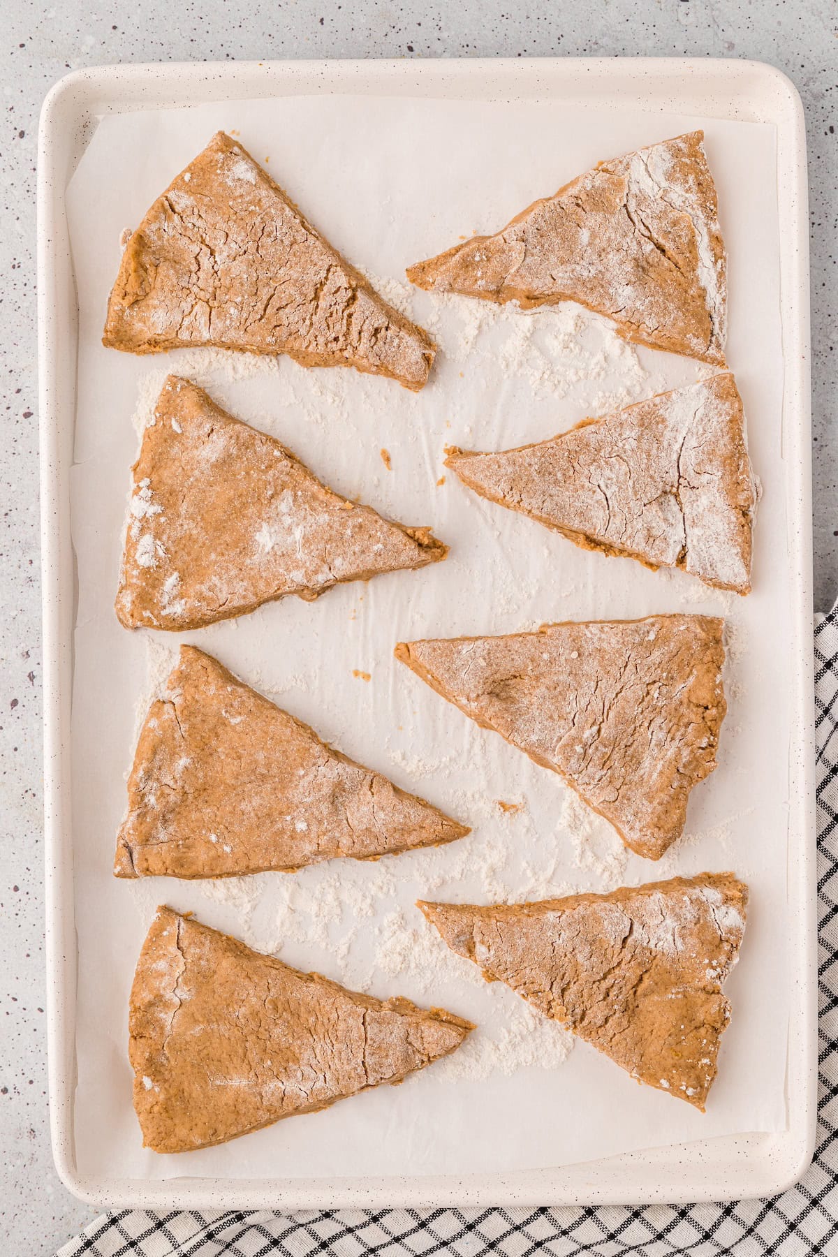 Eight unbaked Gluten-Free Pumpkin Scones on a parchment-lined baking sheet, ready for the oven.