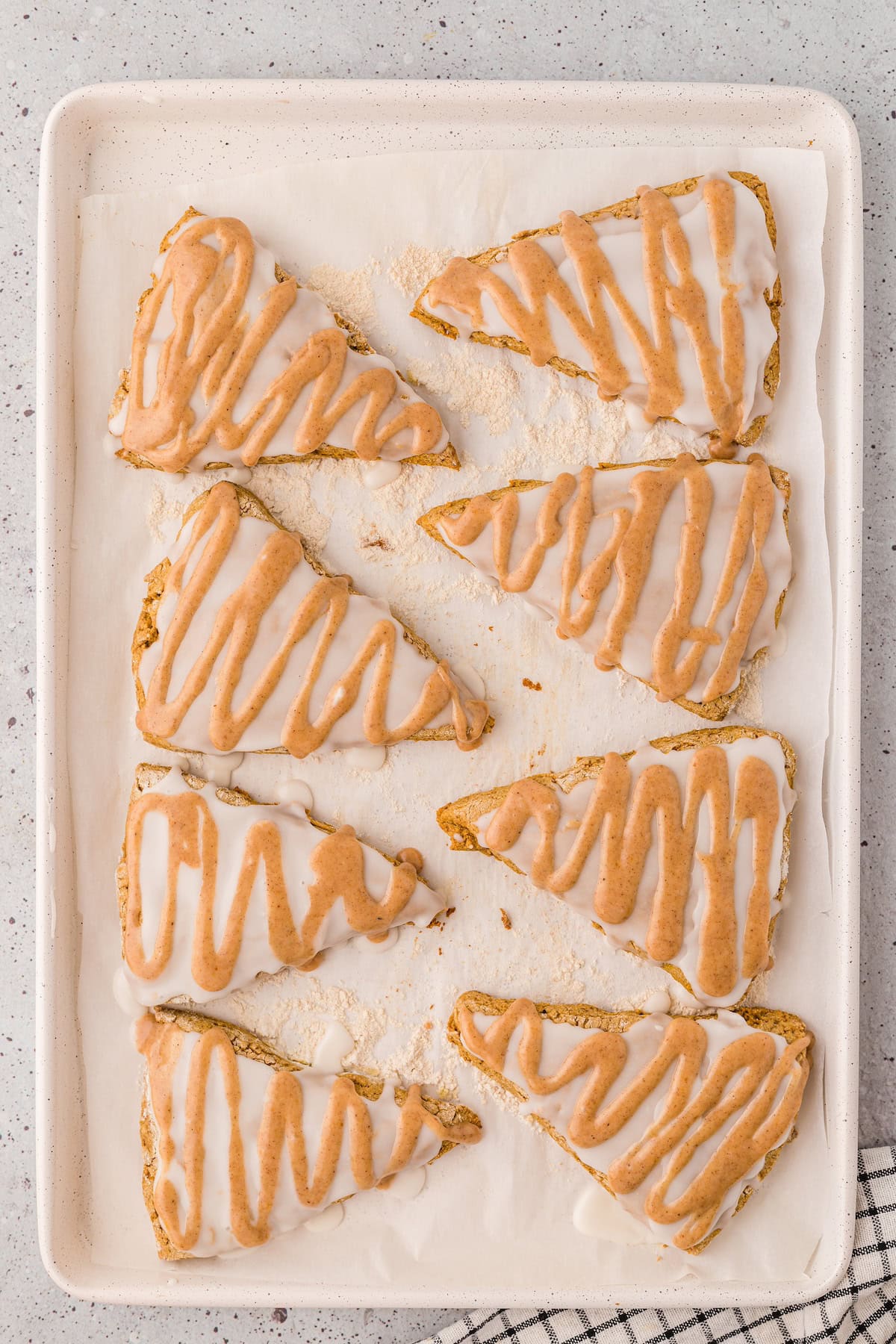 Eight gluten-free pumpkin scones arranged on a baking sheet lined with parchment paper.