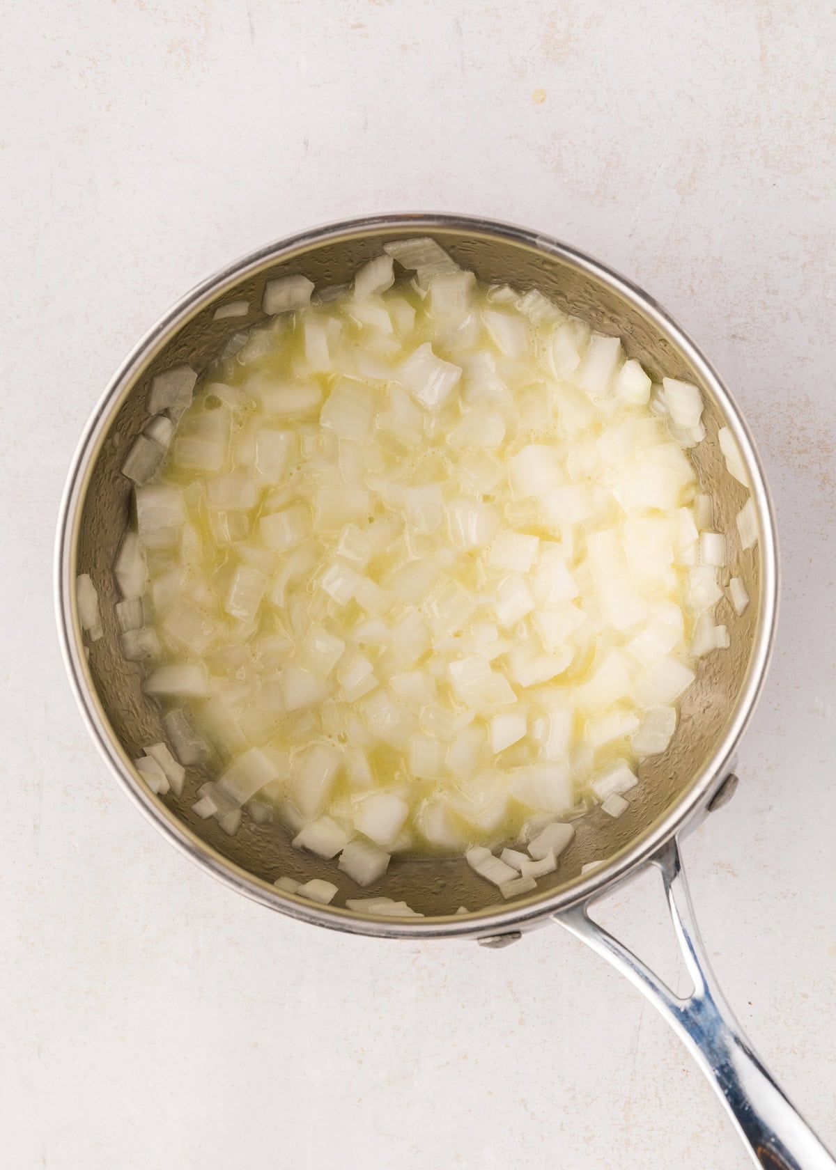 Saucepan with melted butter and onions cooking.