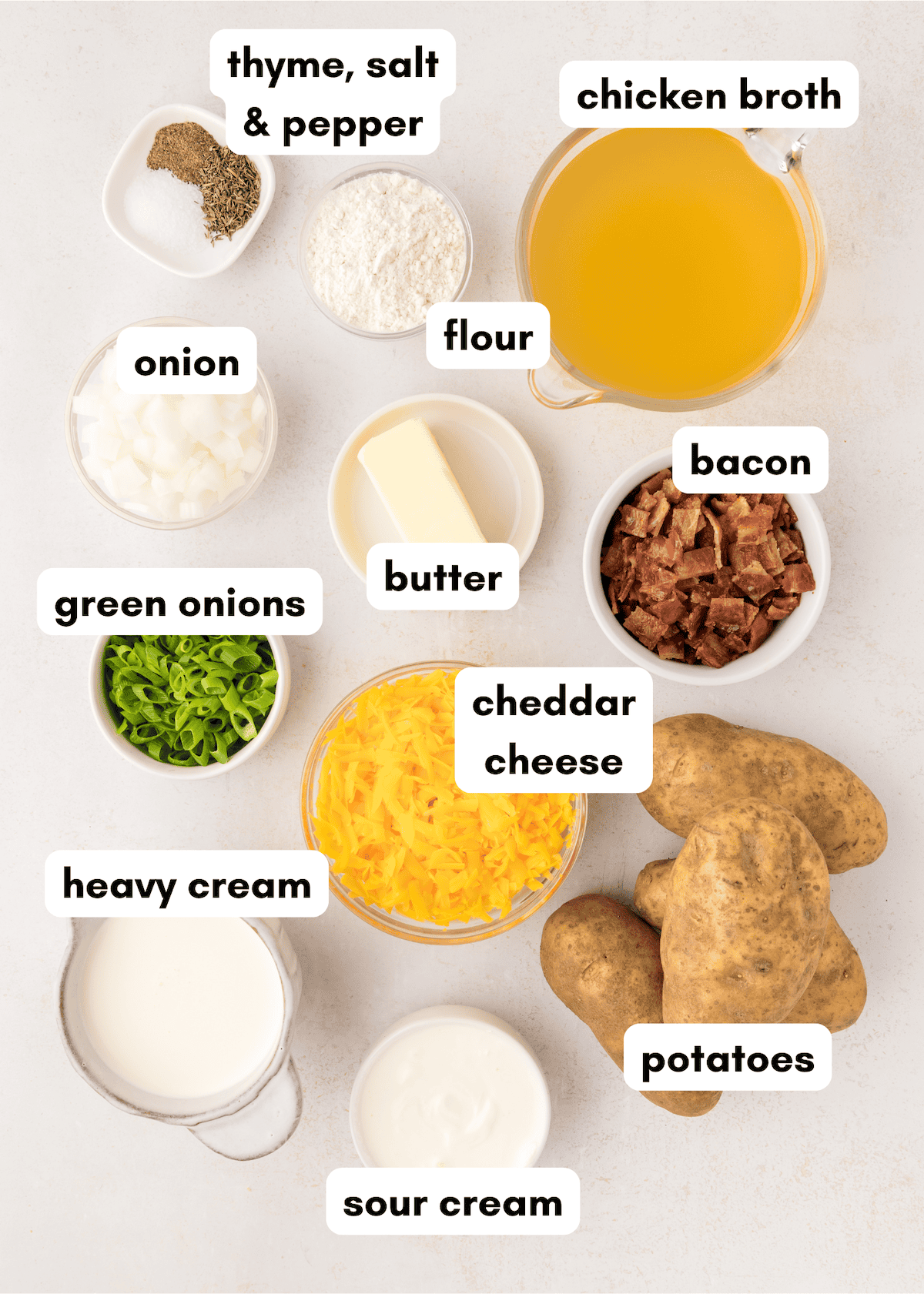 Ingredients for crockpot potato soup such as cheese, green onions, bacon, and more.