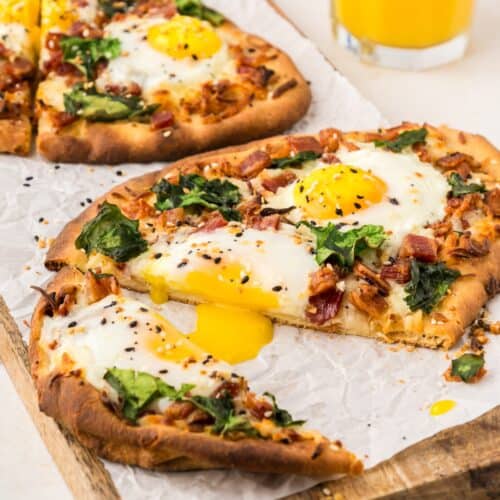 breakfast flatbread served with orange juice, on a wooden cutting board
