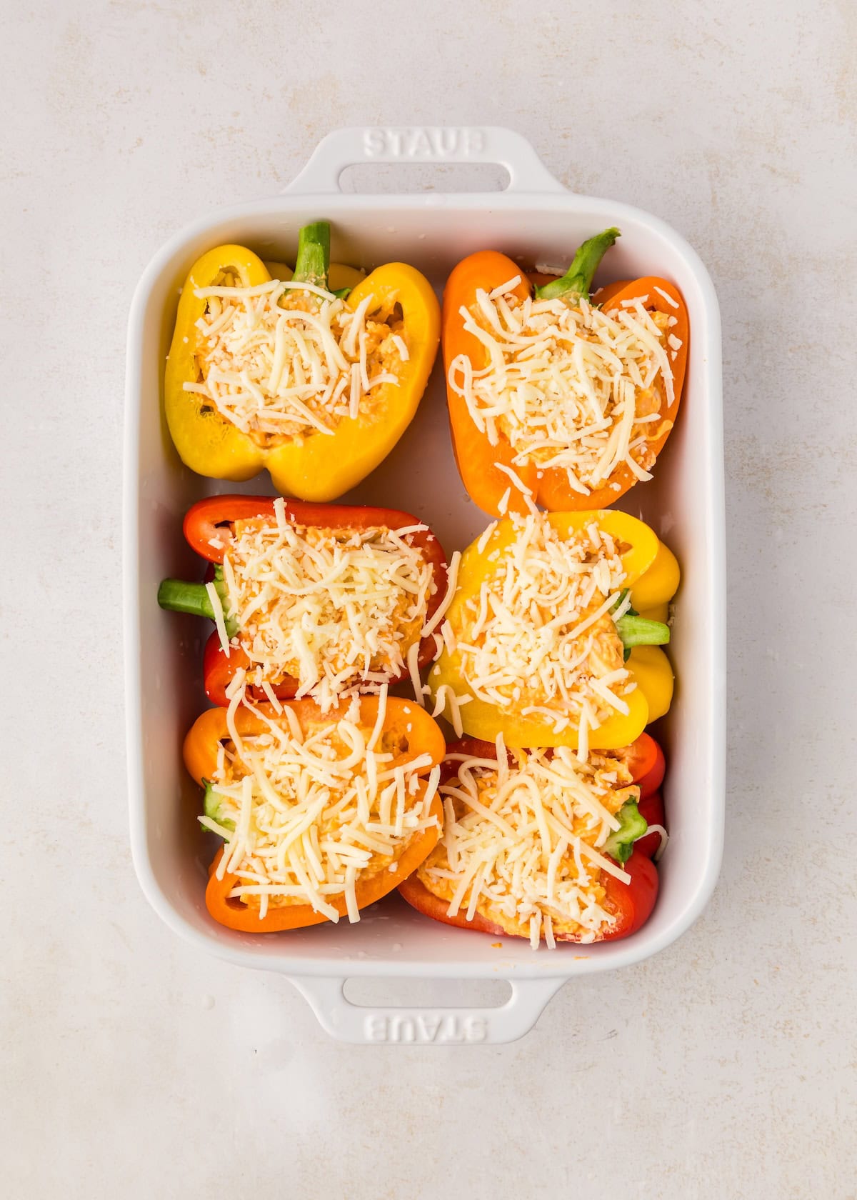 Buffalo Chicken Stuffed Peppers topped with cheese in a white baking dish, ready to bake.