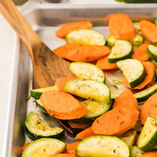 roasted carrots and zucchini on baking sheet with spoon
