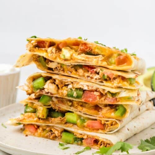 Chicken Quesadillas sliced and stacked, showing melty cheese, chicken, and veggies.