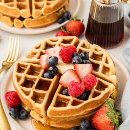 homemade waffles on a plate with syrup and berries