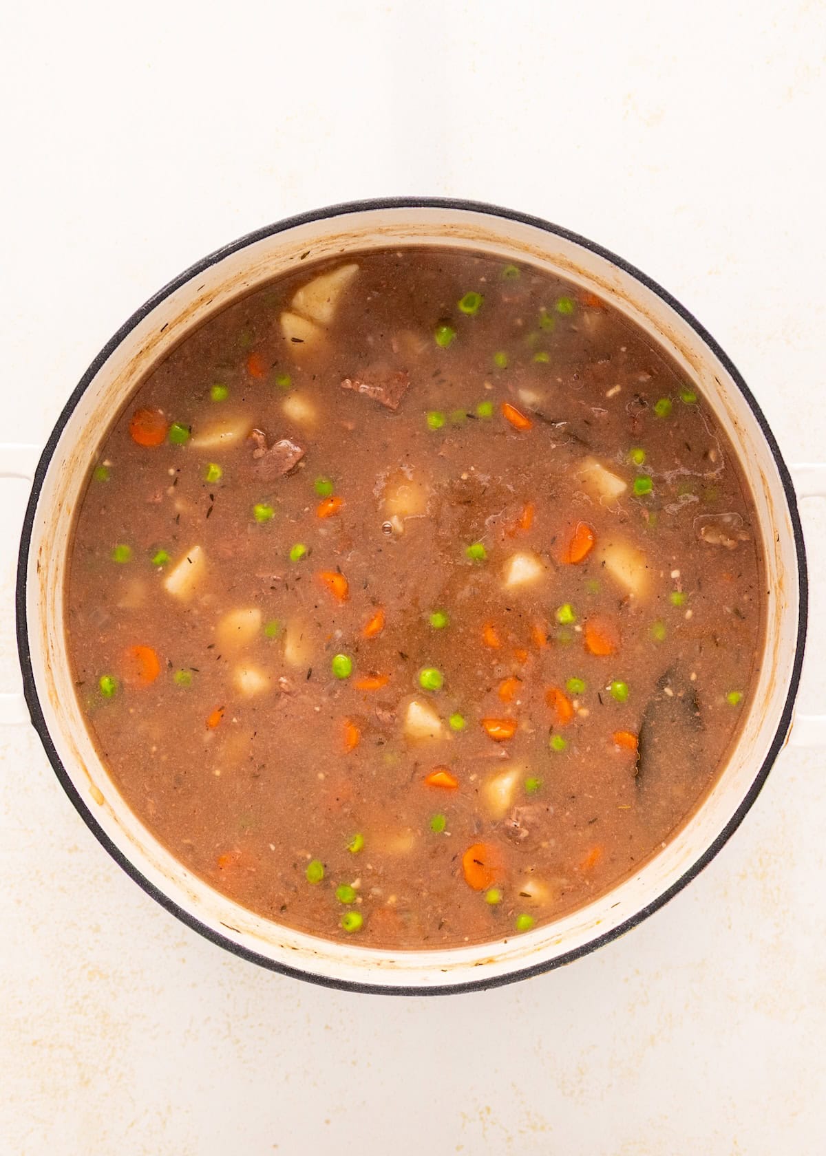 A pot of Beef Vegetable Stew with carrots, potatoes, peas, and a rich brown broth.