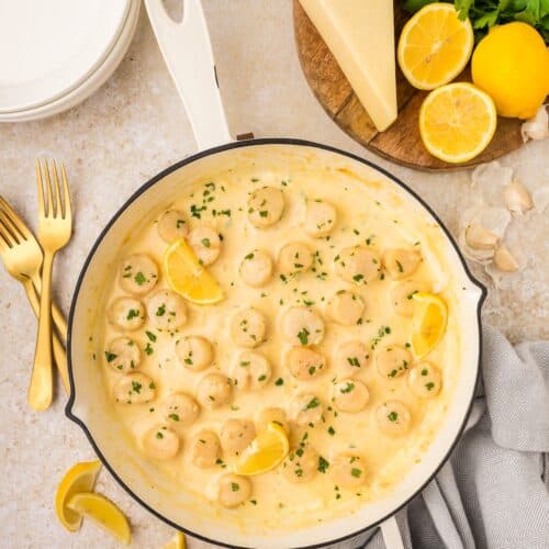 Pan of creamy lemon garlic shrimp and Creamy Garlic Scallops, garnished with lemon and parsley.