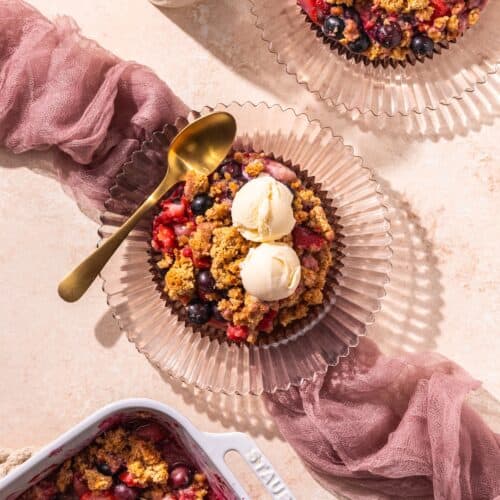 Mixed Berry Cobbler served with ice cream on a pink plate.