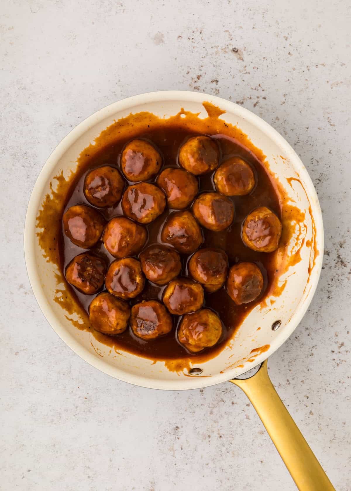 A pan of BBQ Chicken Meatballs covered in brown sauce on a light countertop.