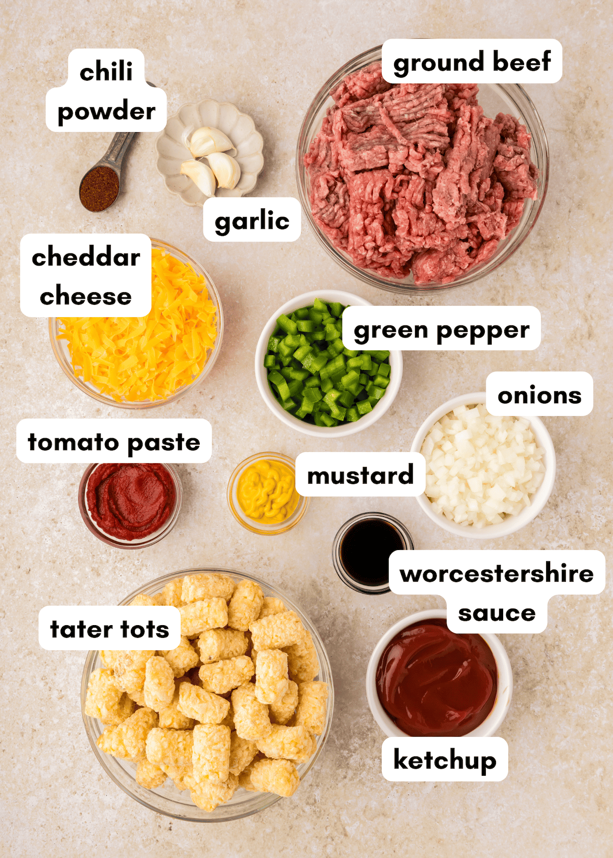 Ingredients for a Sloppy Joe Casserole include ground beef, tater tots, veggies, cheese, and sauces.