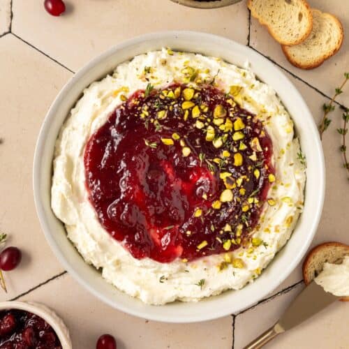 Cranberry Whipped Feta Dip with cranberry sauce, crushed pistachios, and bread to dip.