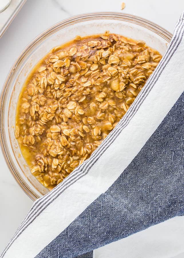A bowl of baked oatmeal partially covered by a blue and white striped cloth.