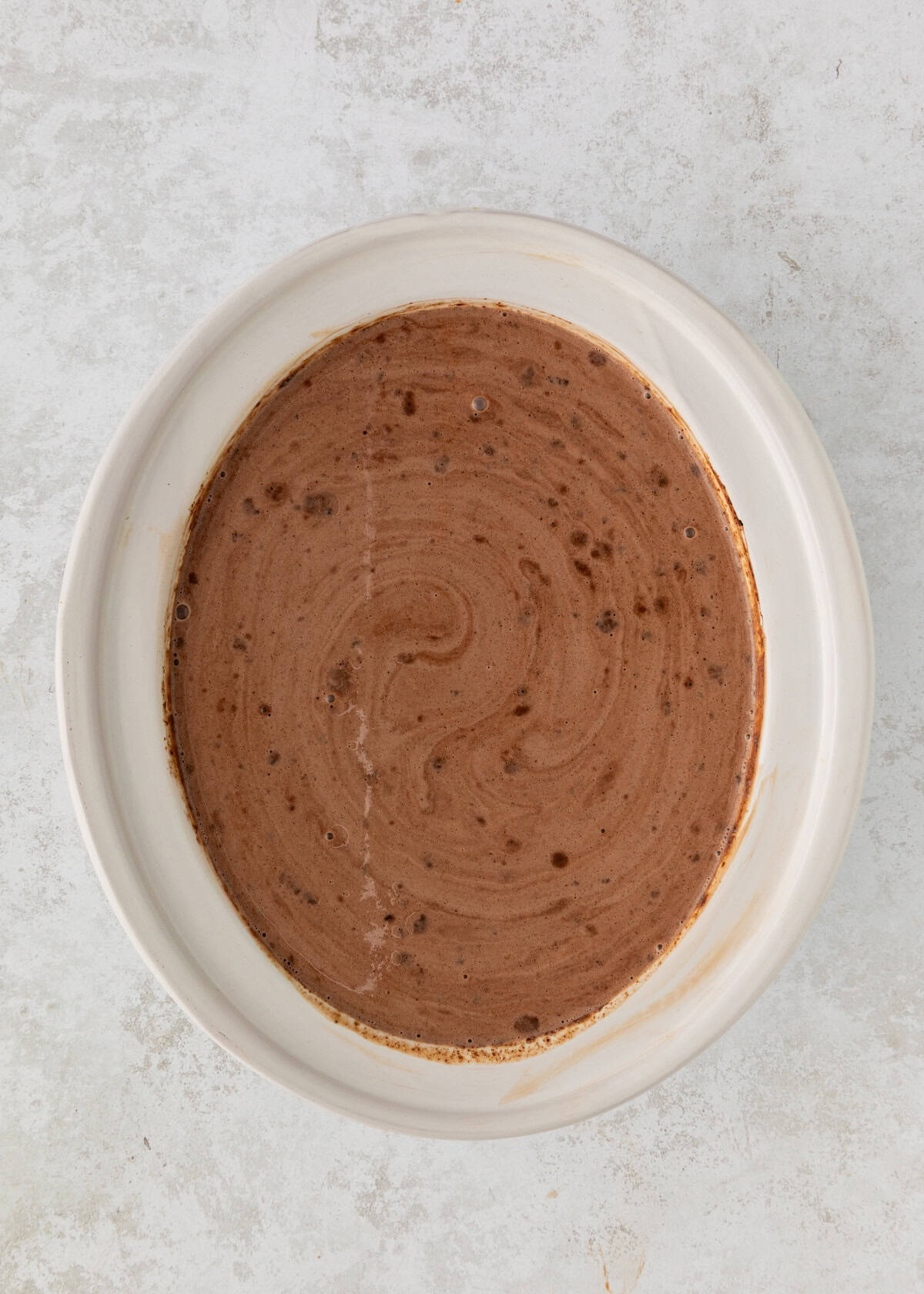 A white bowl filled with swirled chocolate batter on a light textured surface.