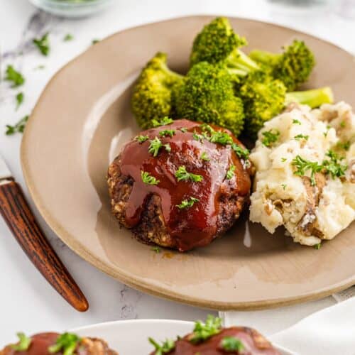 A plate with meatloaf, mashed potatoes, broccoli, and parsley garnish.