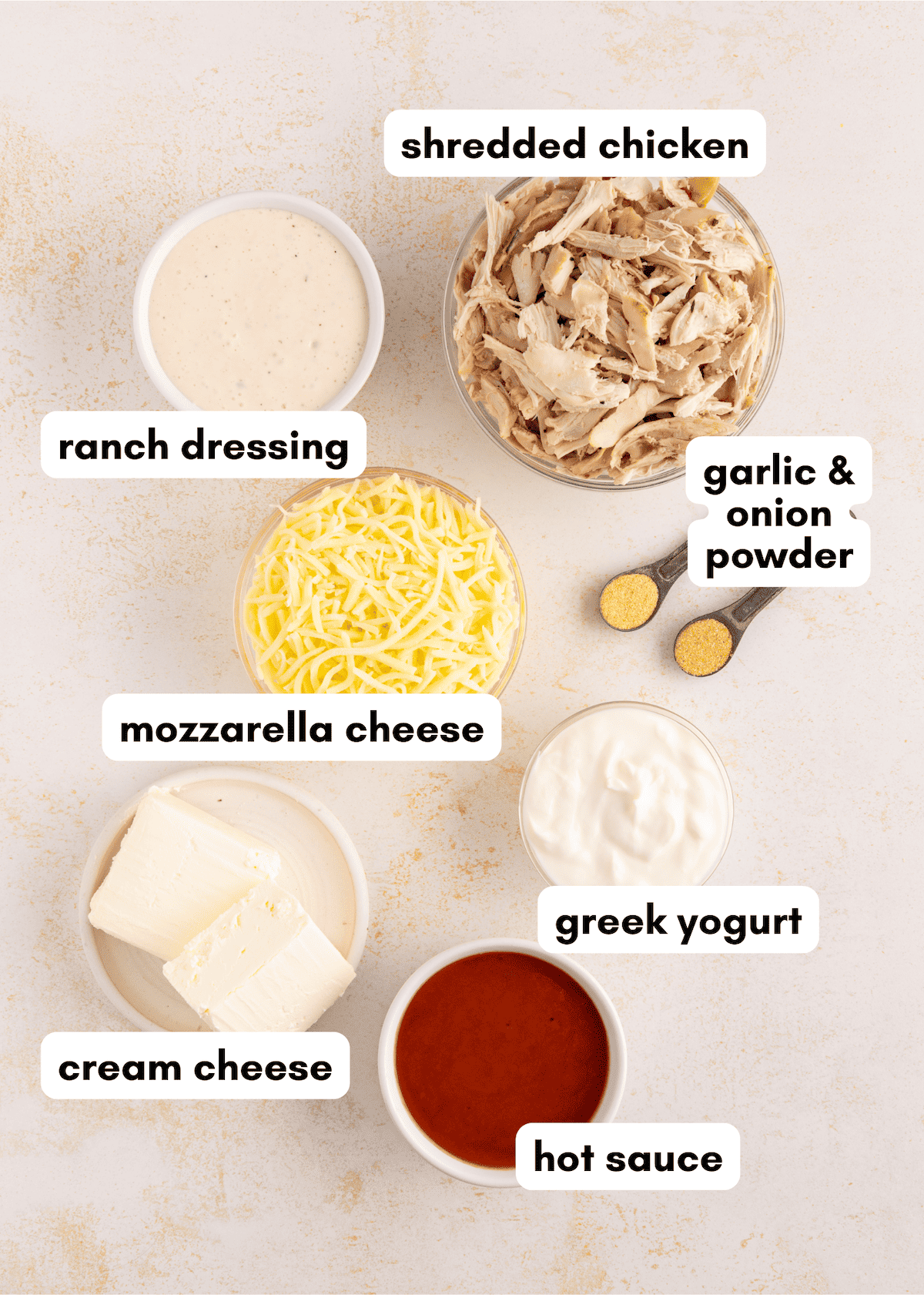 Ingredients for buffalo chicken dip: shredded chicken, cheeses, yogurt, ranch, hot sauce, powders.