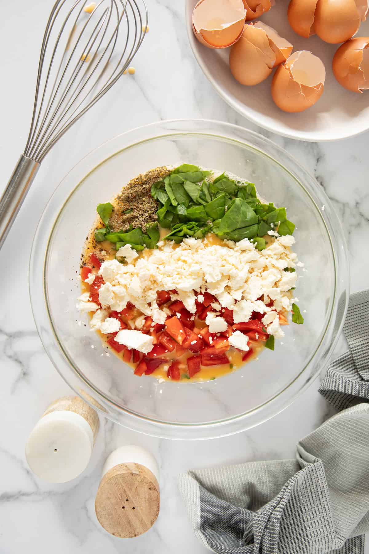 A bowl with eggs, vegetables, and feta cheese-perfect for Feta Spinach Egg Muffins prep.
