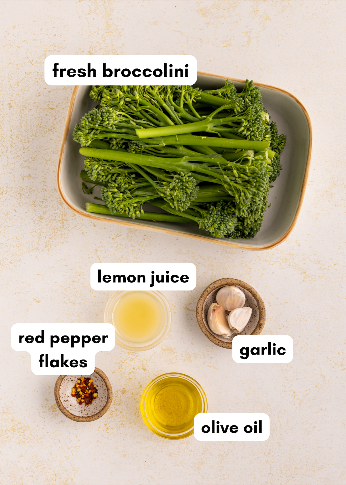 A bowl of sautéed broccolini with garlic, lemon juice, red pepper flakes, and olive oil on a table.