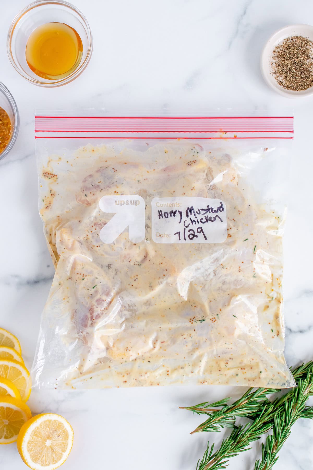 A ziplock bag labeled Honey Mustard Chicken with marinade on a white countertop.