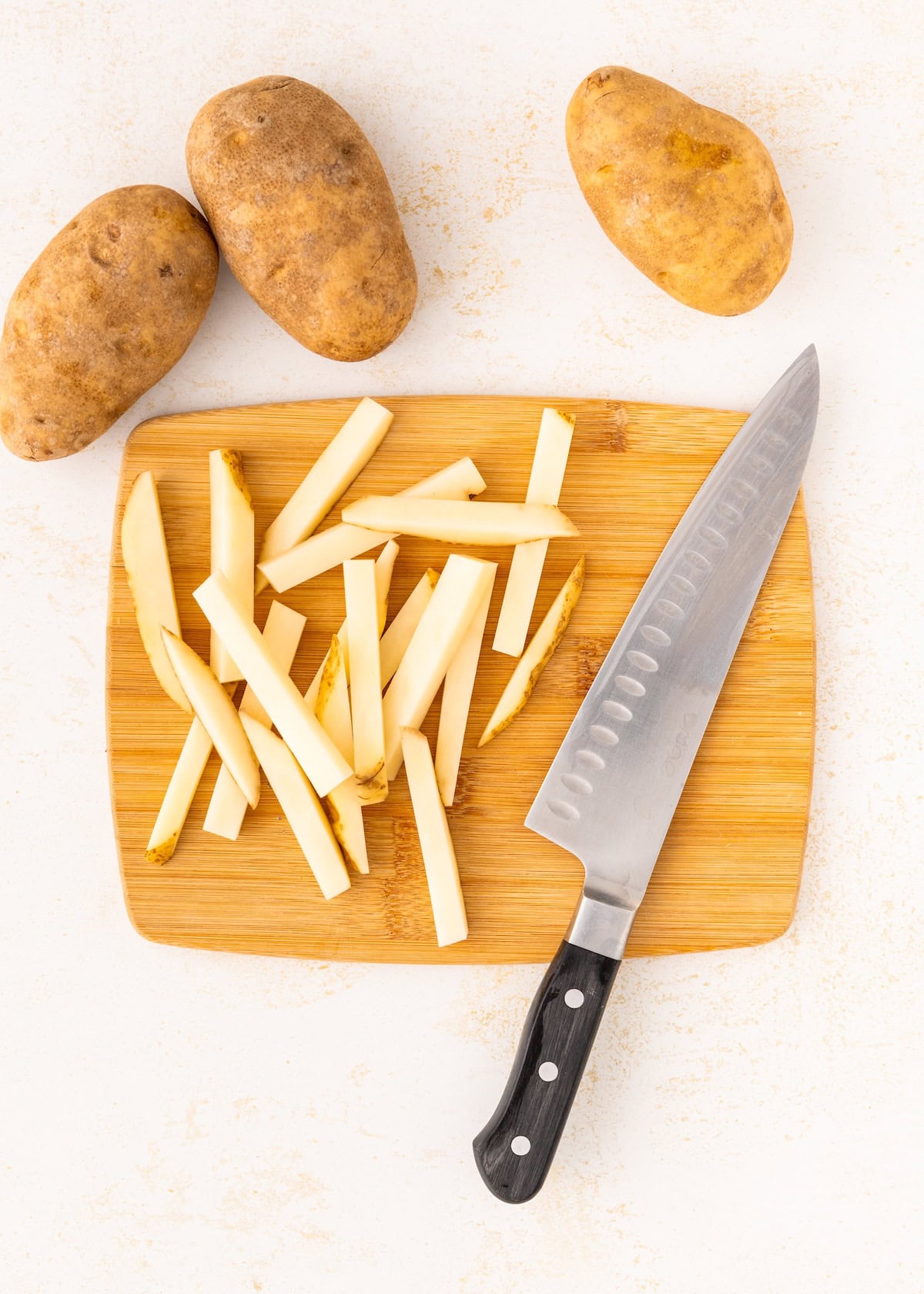 A knife next to potatoes.