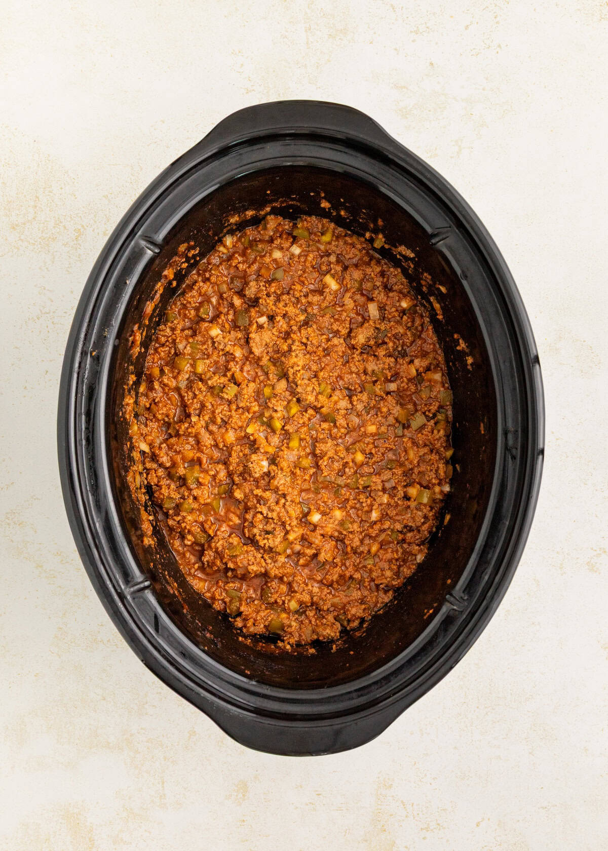 Slow cooker filled with cooked ground meat in a tomato-based sauce, seen from above.