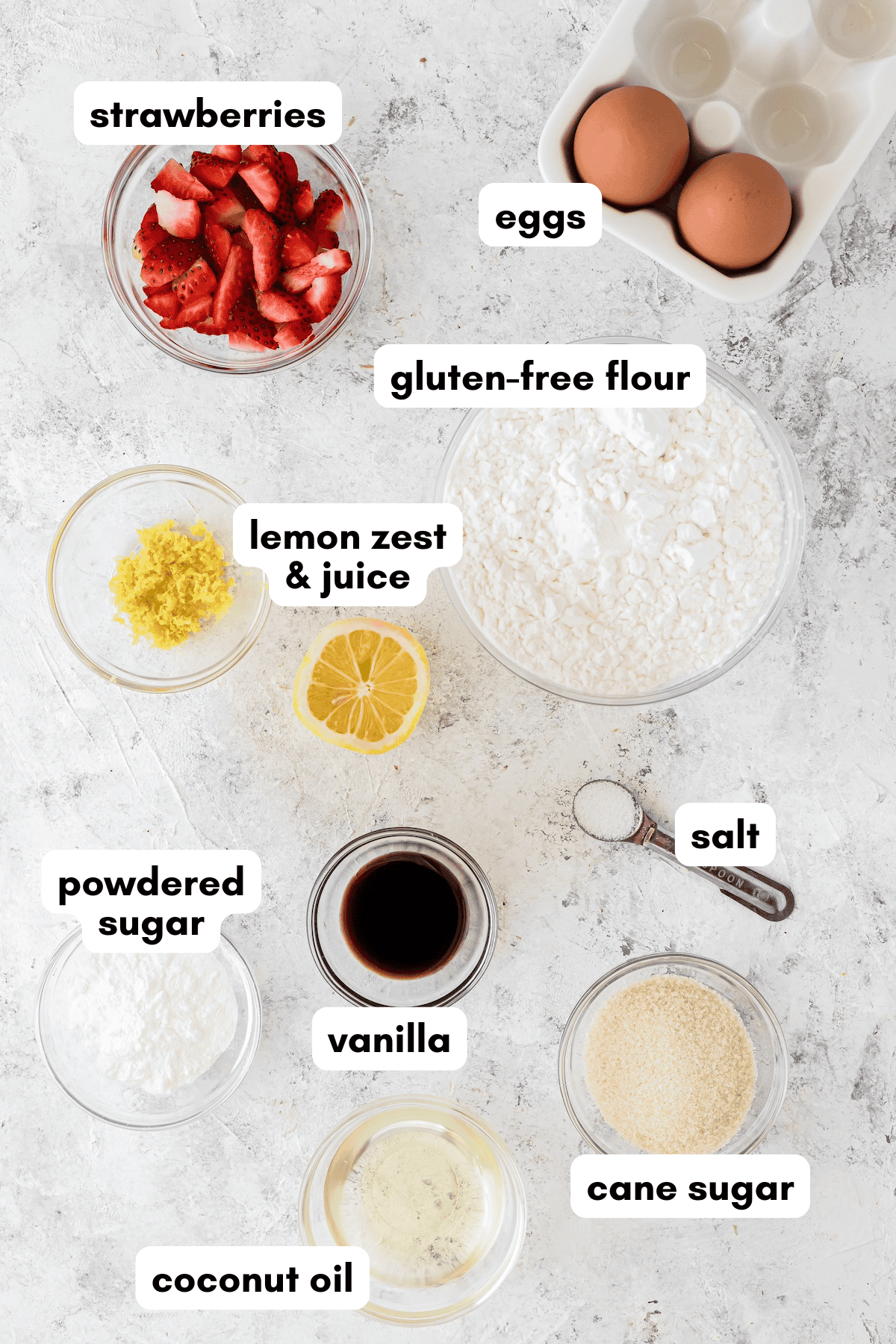 Baking ingredients including strawberries, eggs, coconut oil, flours, sugars, and lemon.