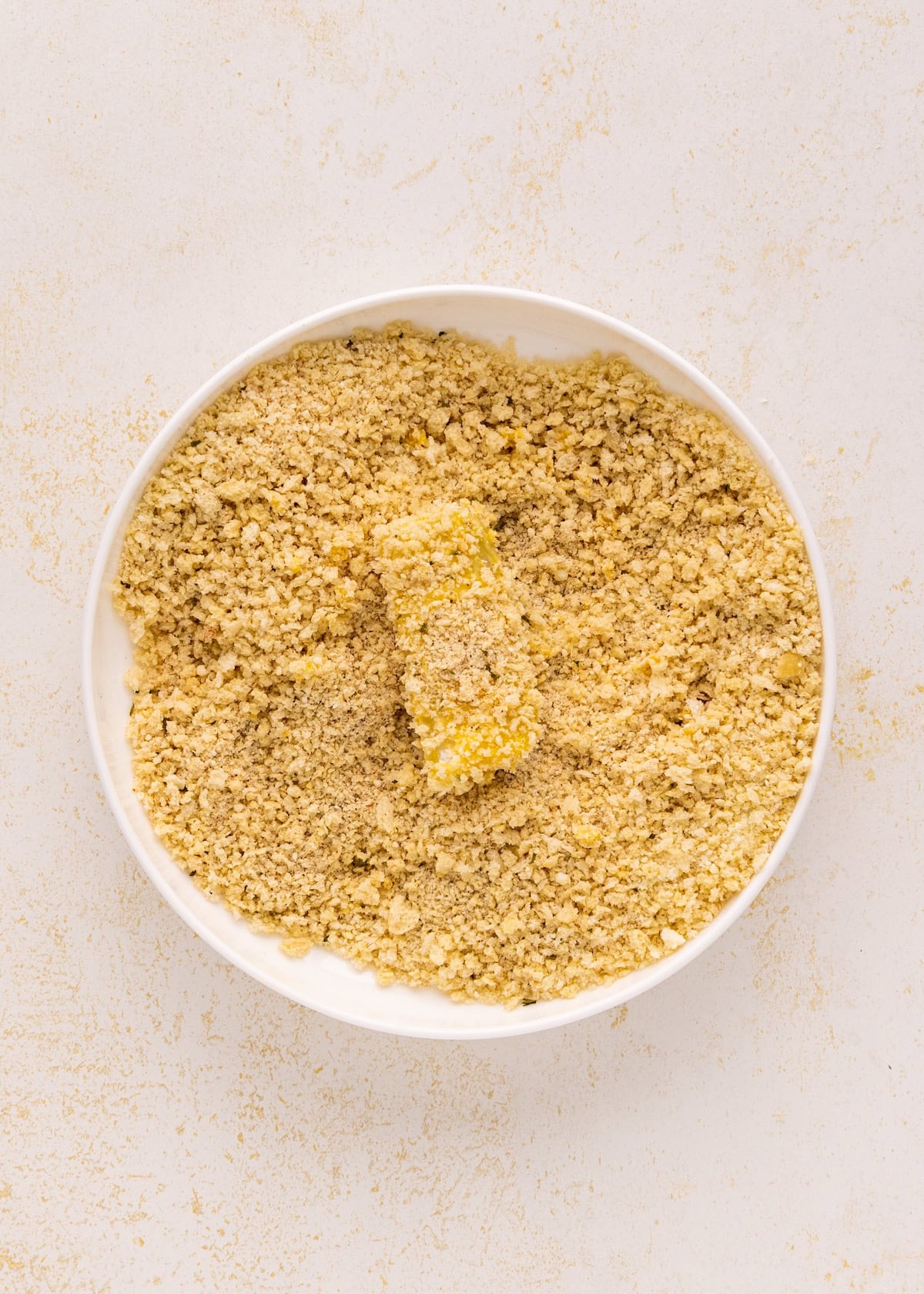 Homemade Fish Sticks being coated in a bowl of breadcrumbs for a crisp finish.