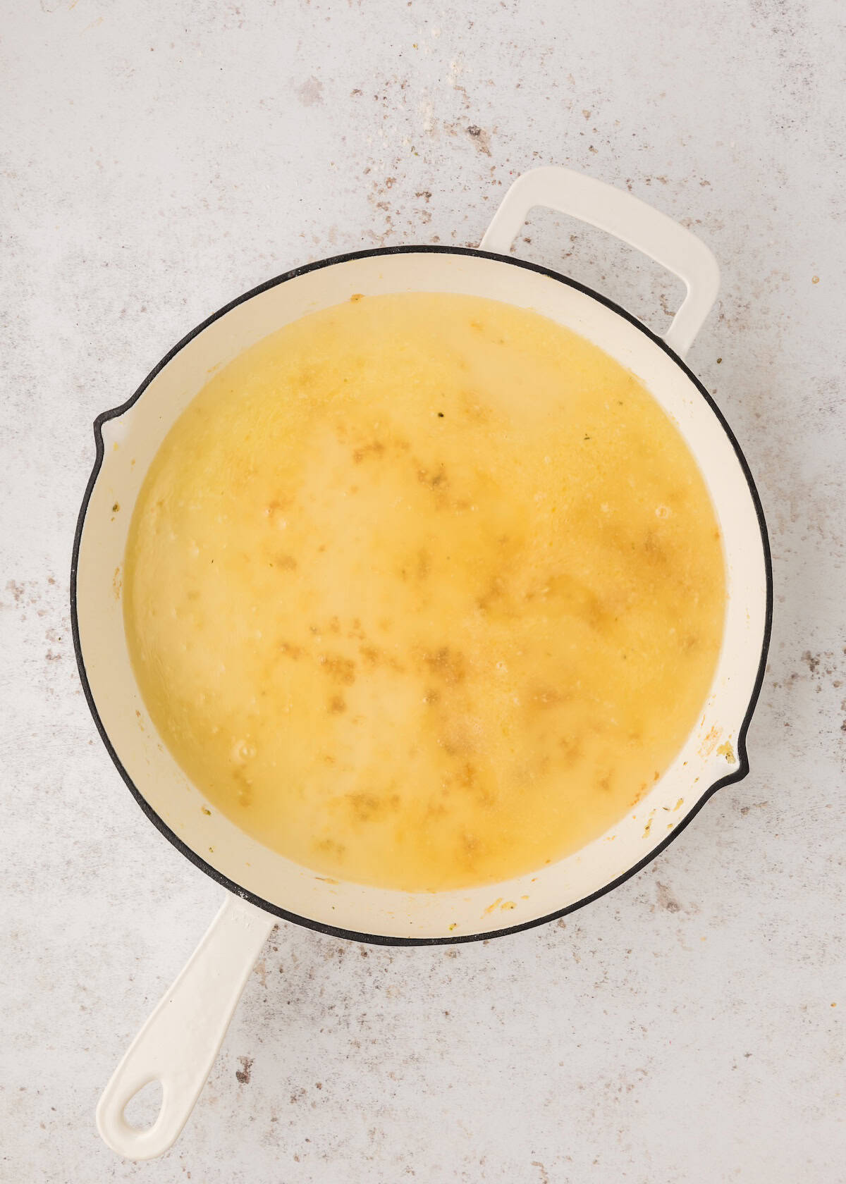 A white pot filled with melted butter on a light-colored surface.
