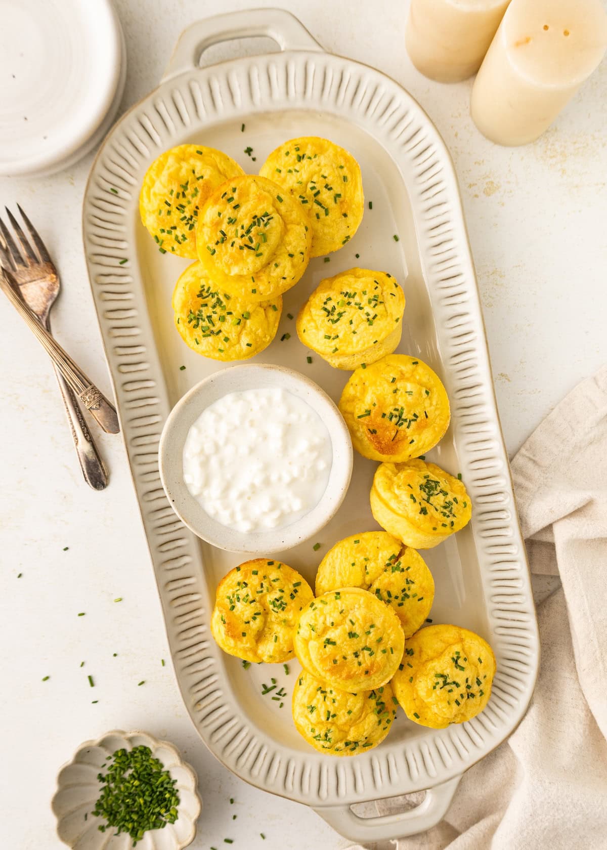 Round savory muffins garnished with herbs, served on a platter with a bowl of white dip.