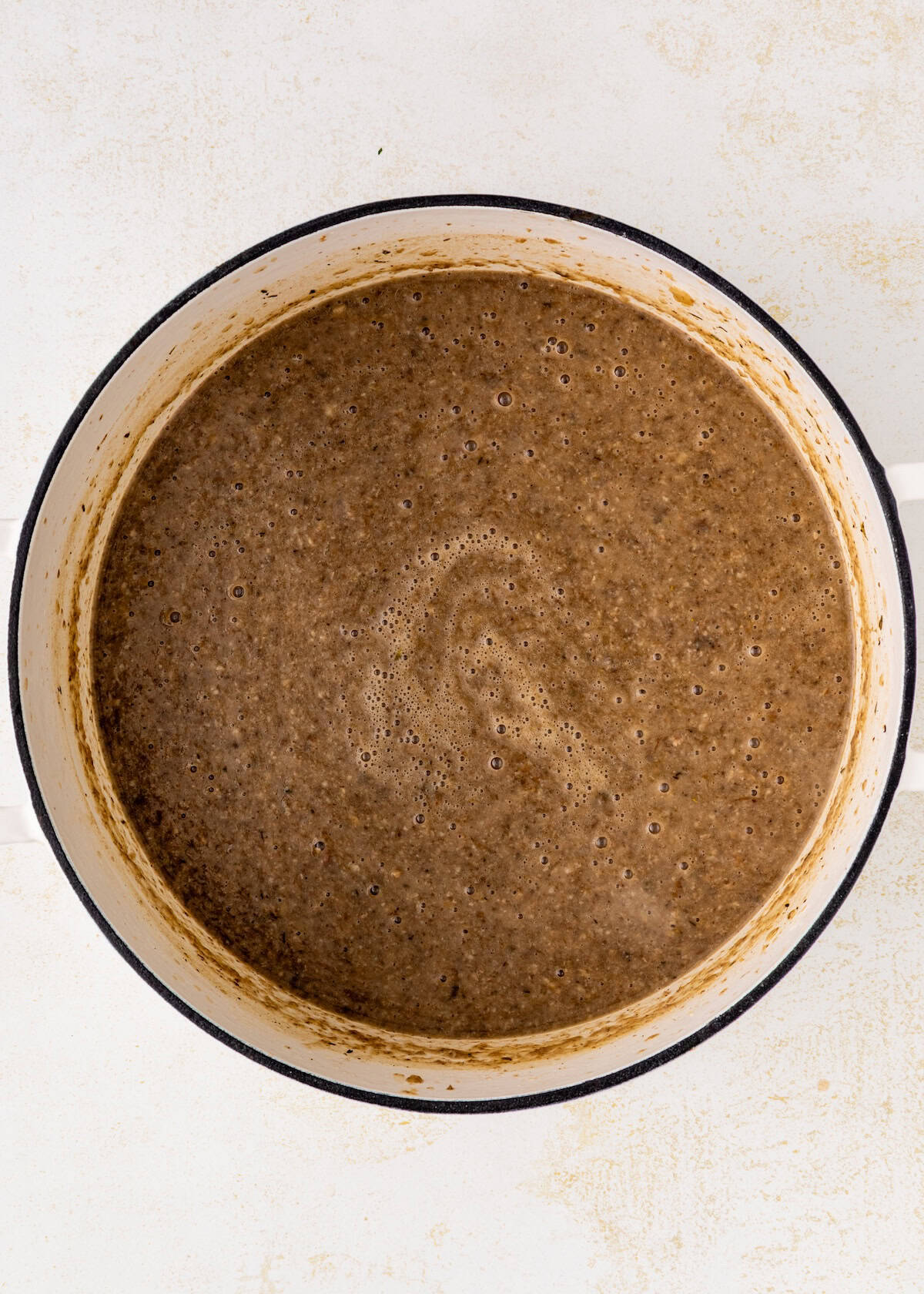 A pot filled with blended brown soup on a light-colored surface.