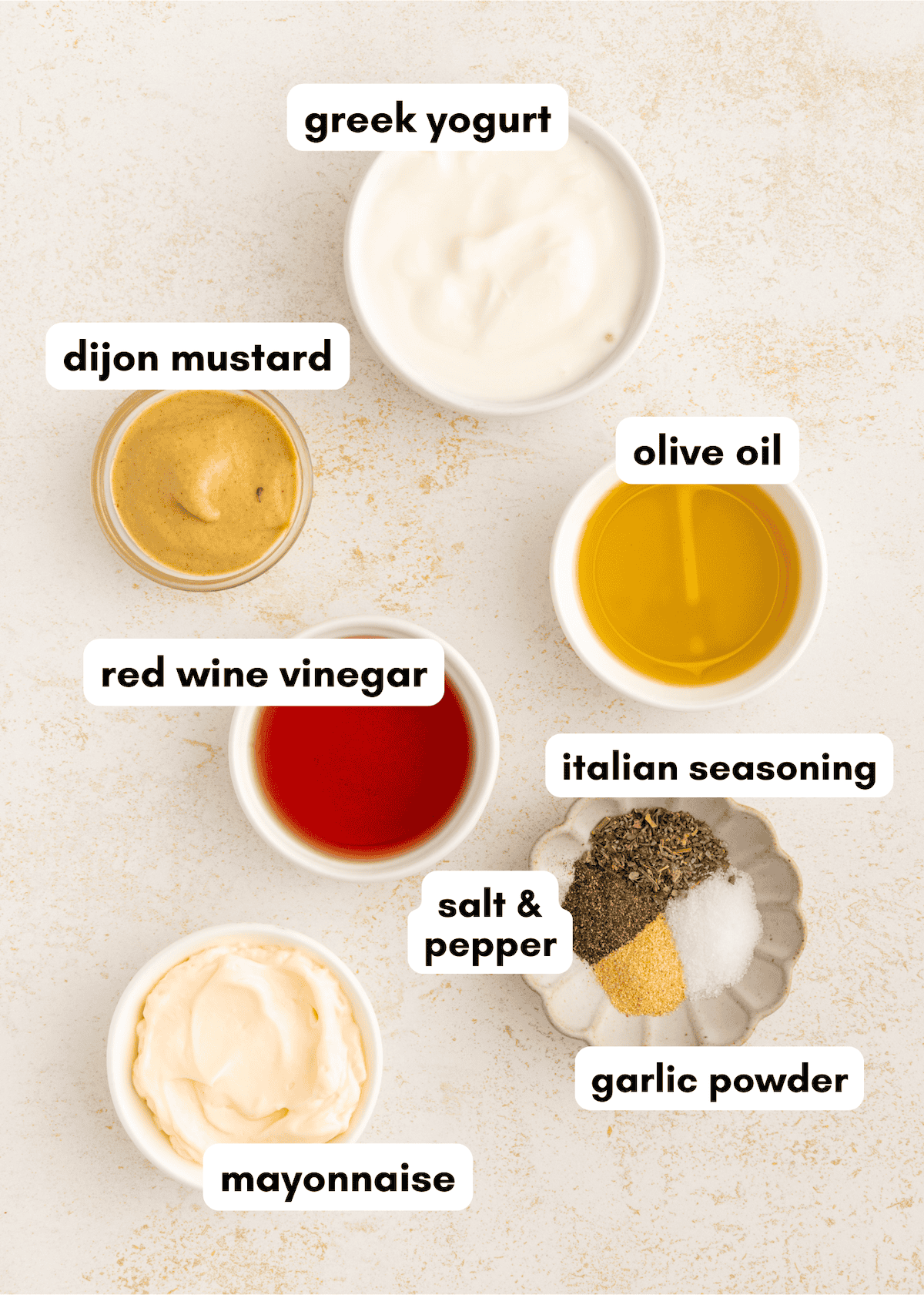 Seven bowls with ingredients for creamy Italian dressing: Greek yogurt, Dijon, mayo, spices, oil.
