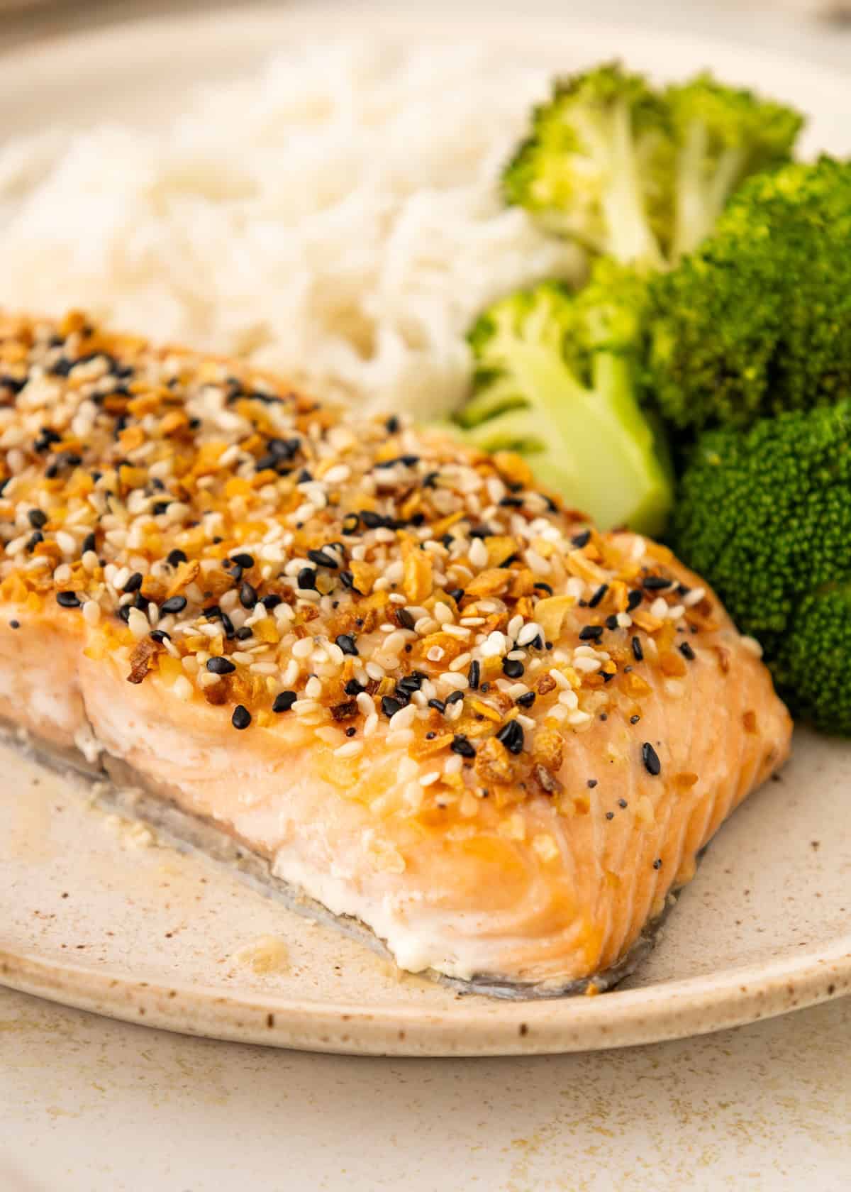 Salmon fillet with seasoning, steamed broccoli, and white rice on a beige plate.