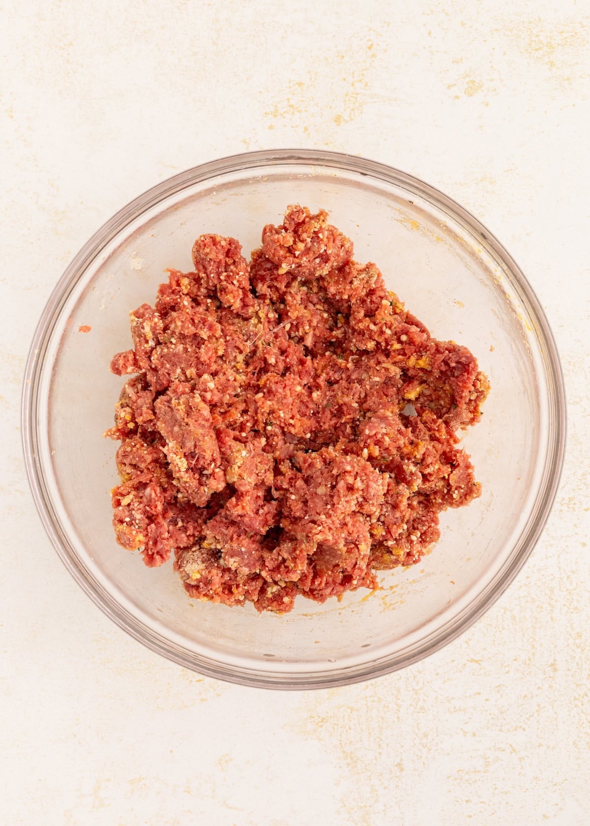 Ground meat mixture for Italian Wedding Soup in a clear glass bowl on a light surface.