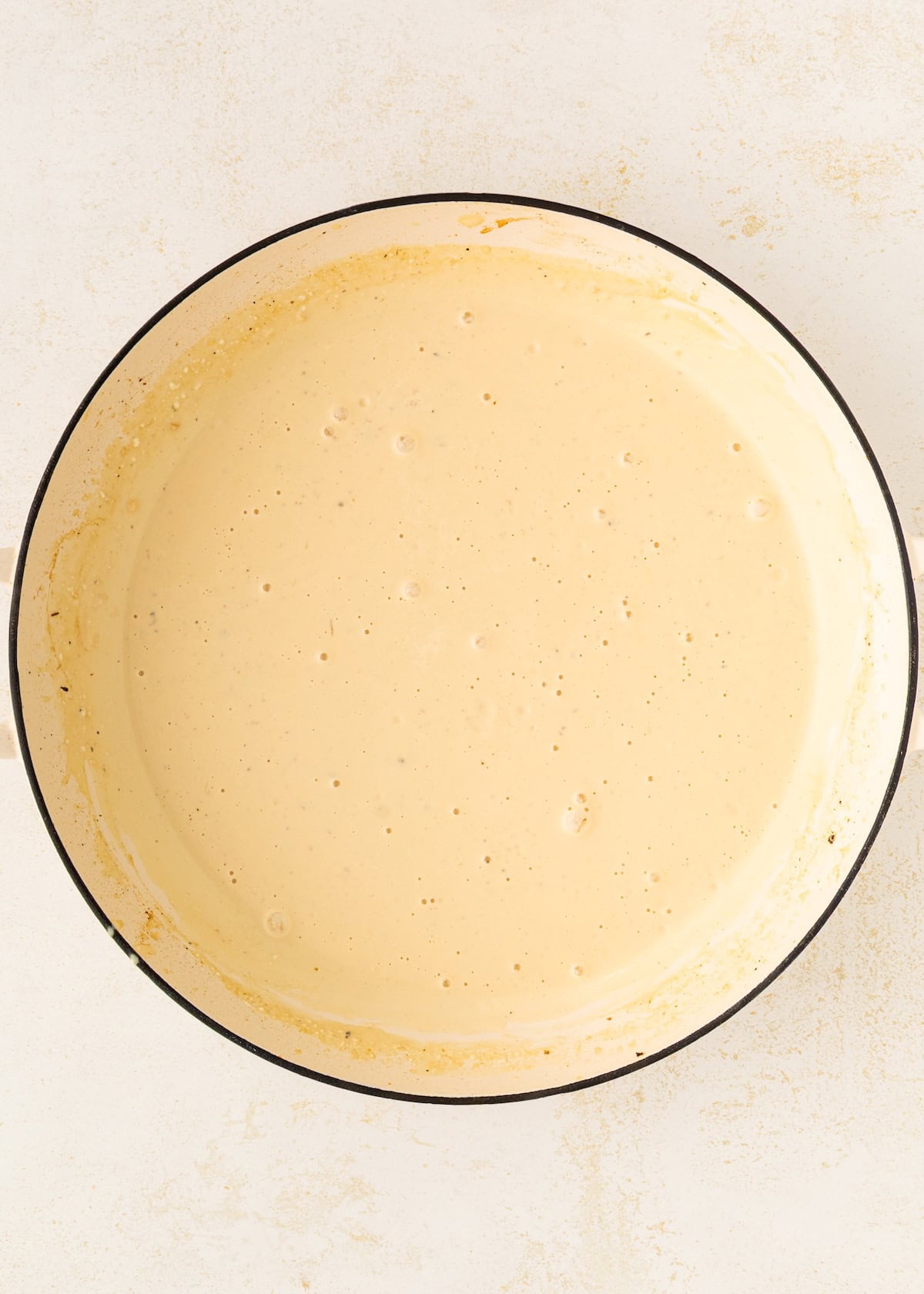 A large pot filled with creamy, light yellow batter or sauce on a white surface.