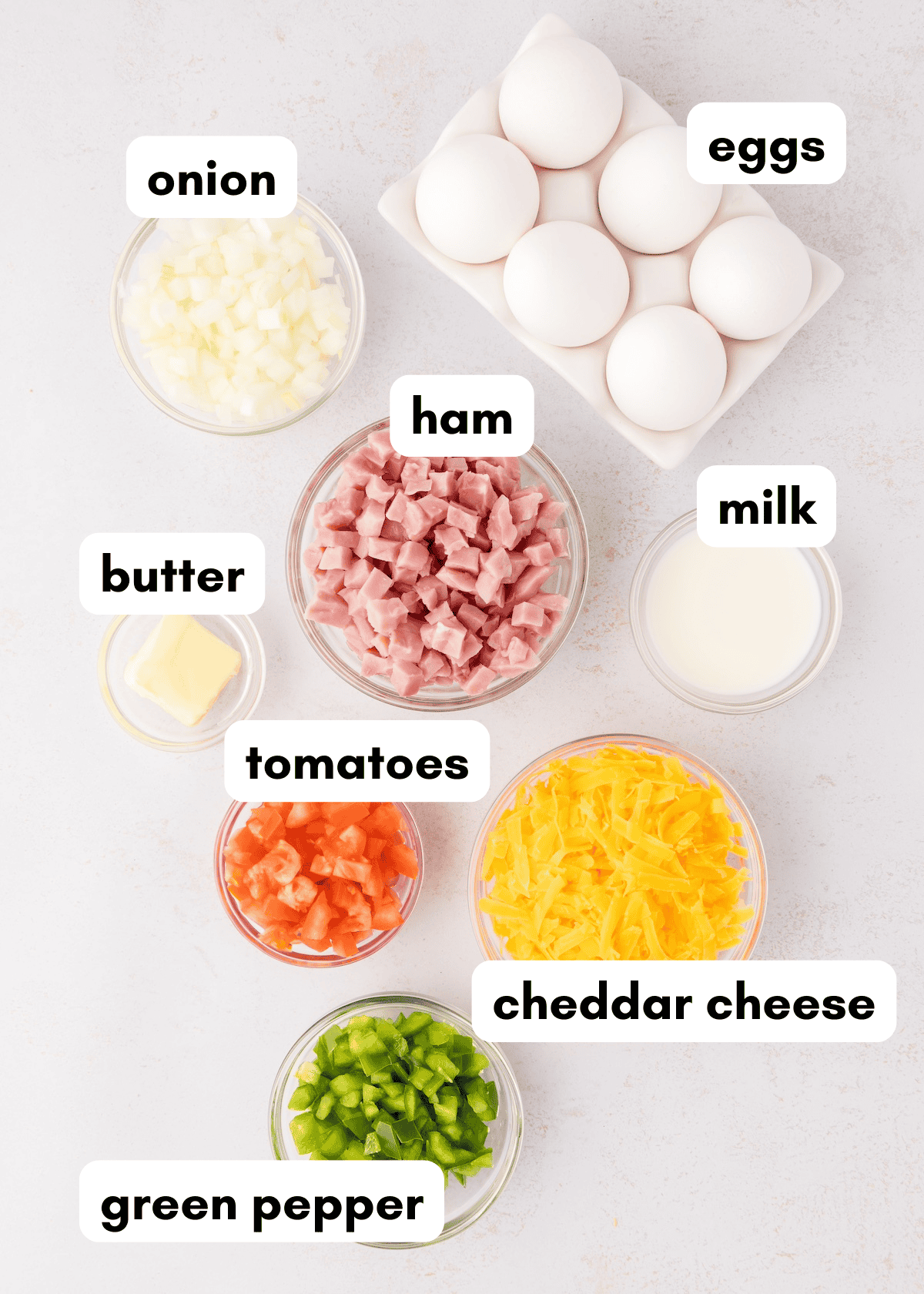 Bowls of Western Scrambled Eggs ingredients: eggs, ham, cheddar cheese, and green pepper.