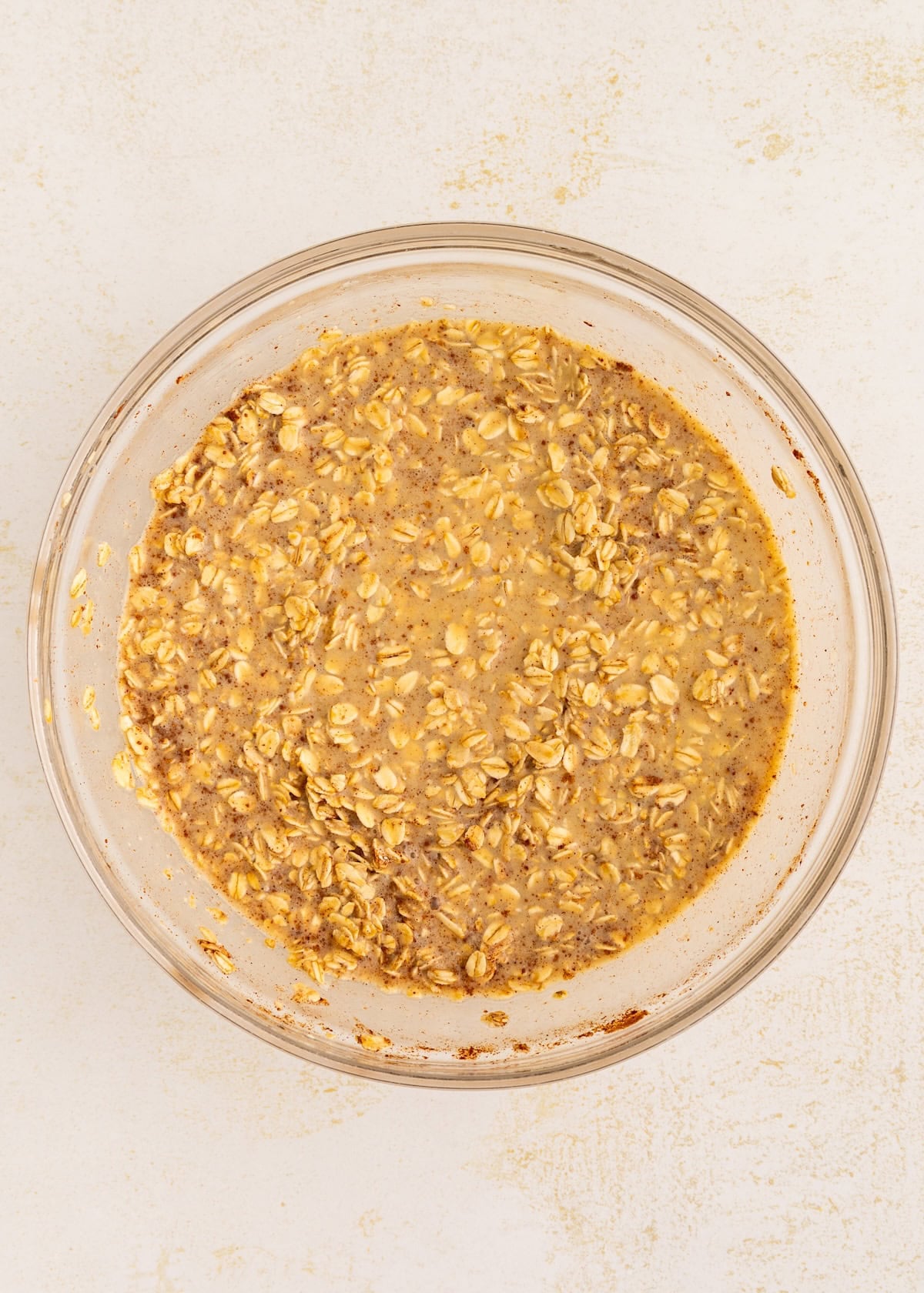 Bowl of mixed oats and liquid on a light surface.