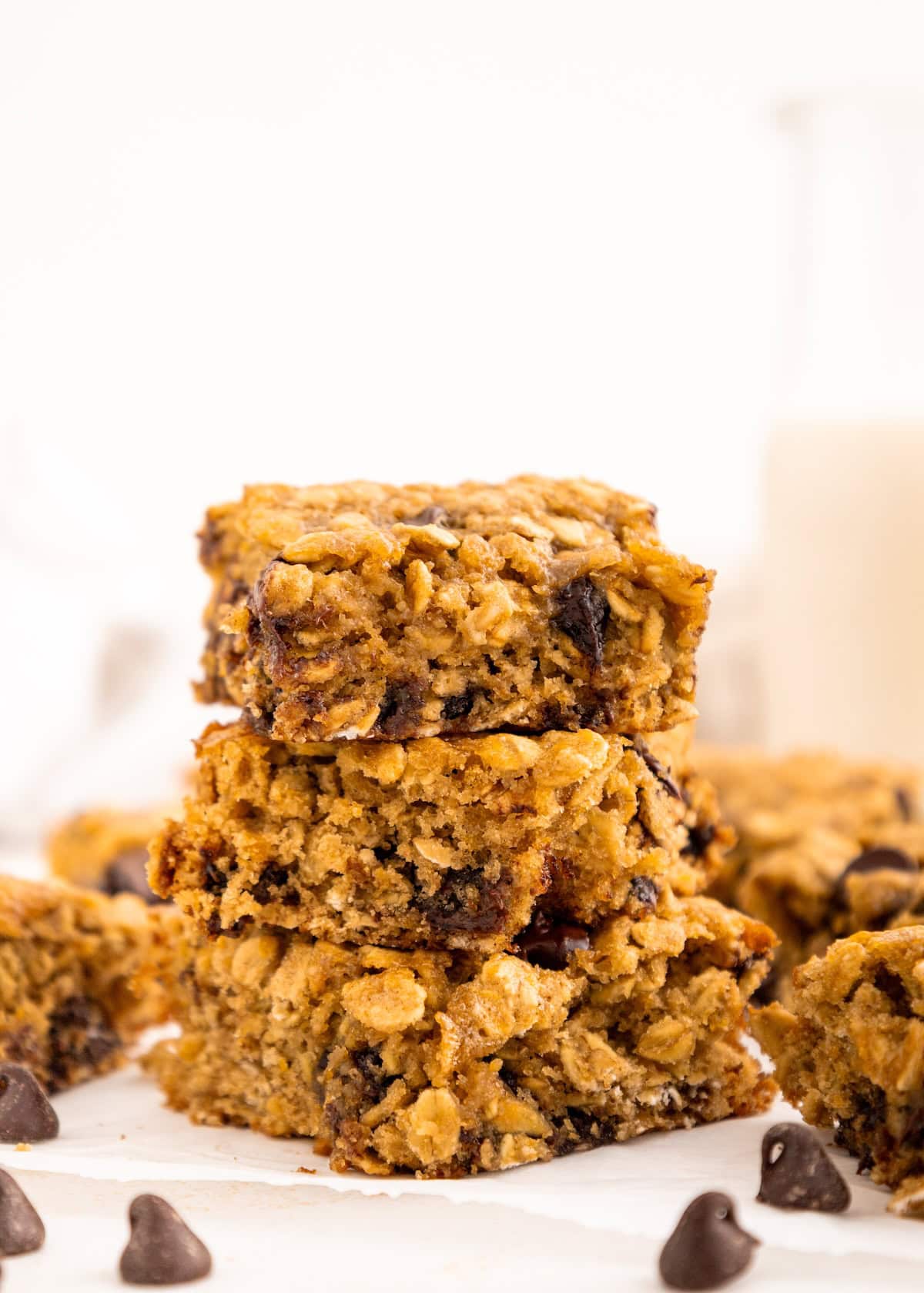 A stack of oatmeal chocolate chip bars with chocolate chips scattered around.