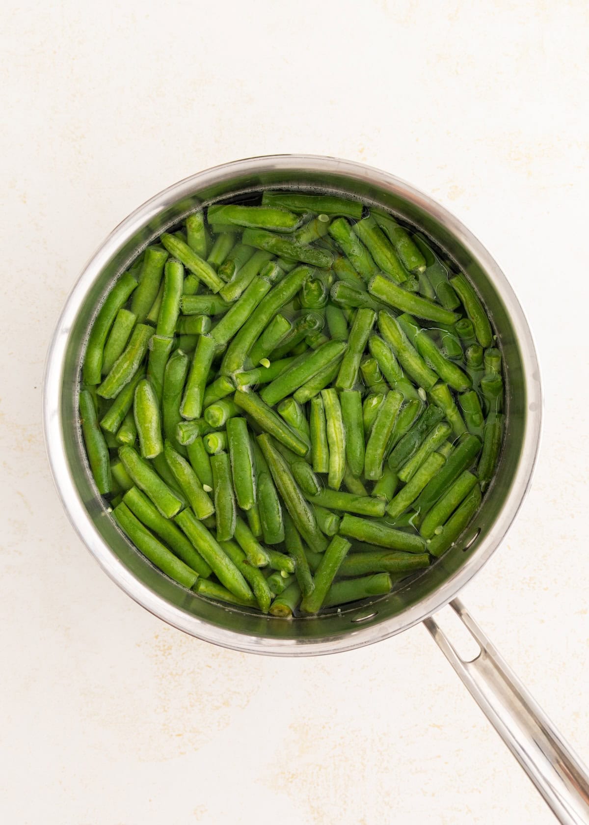 Green beans in a pot of water, viewed from above, ready to be cooked.