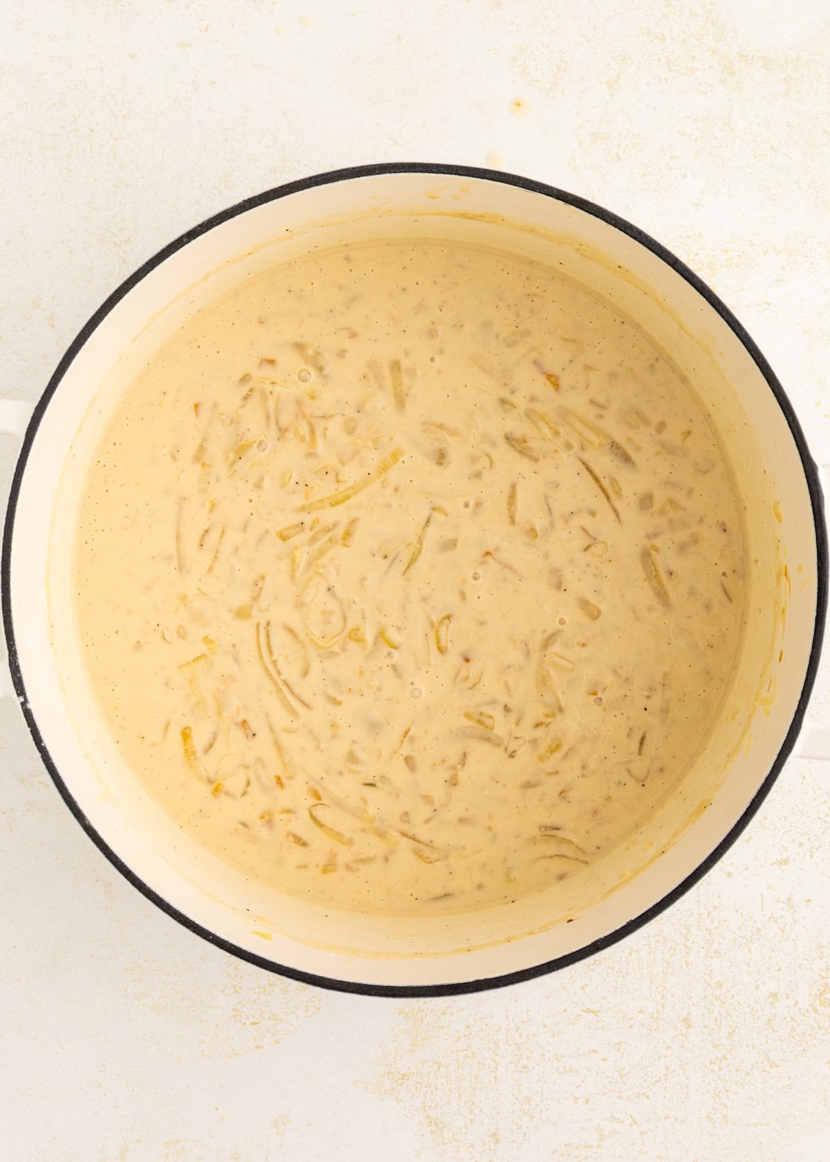 A pot of creamy soup with visible onion slices, viewed from above.
