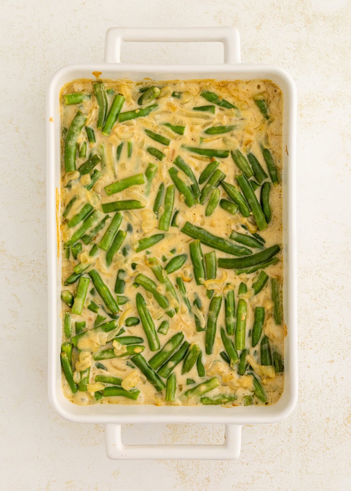 Green bean casserole in a white baking dish on a light surface.
