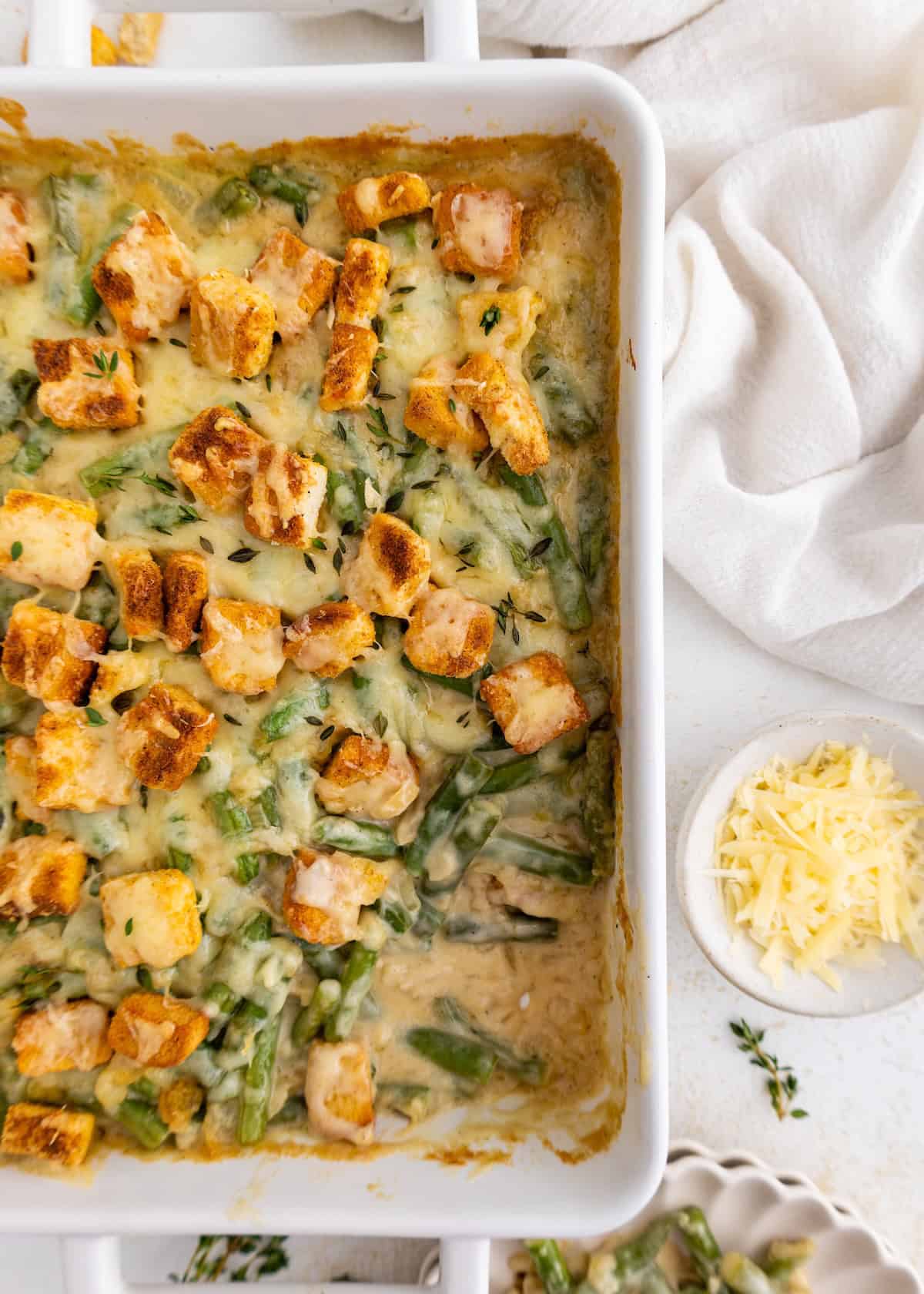 Baked casserole with green beans, croutons, and melted cheese in a white dish.