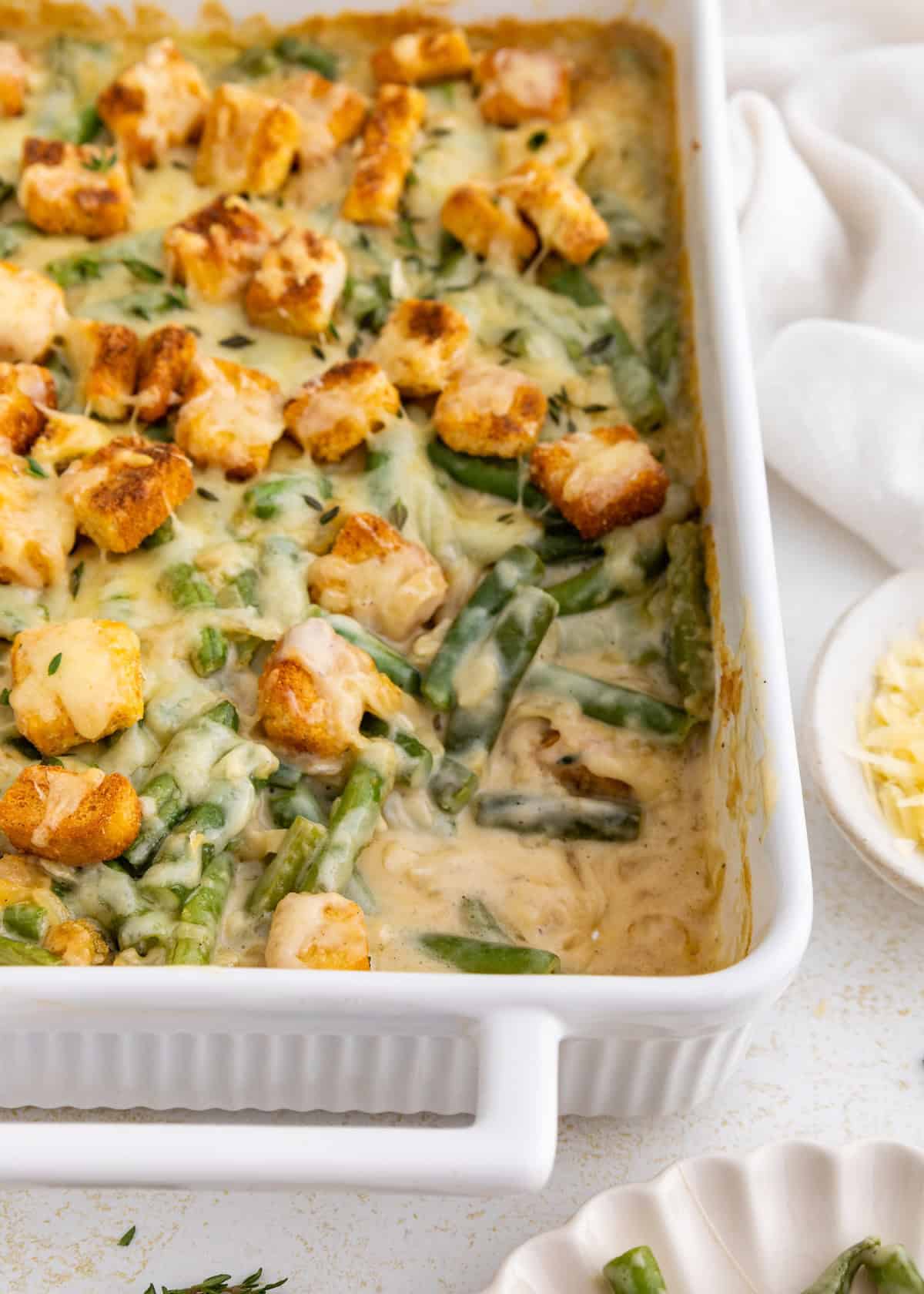 Green bean casserole topped with toasted croutons in a white baking dish.