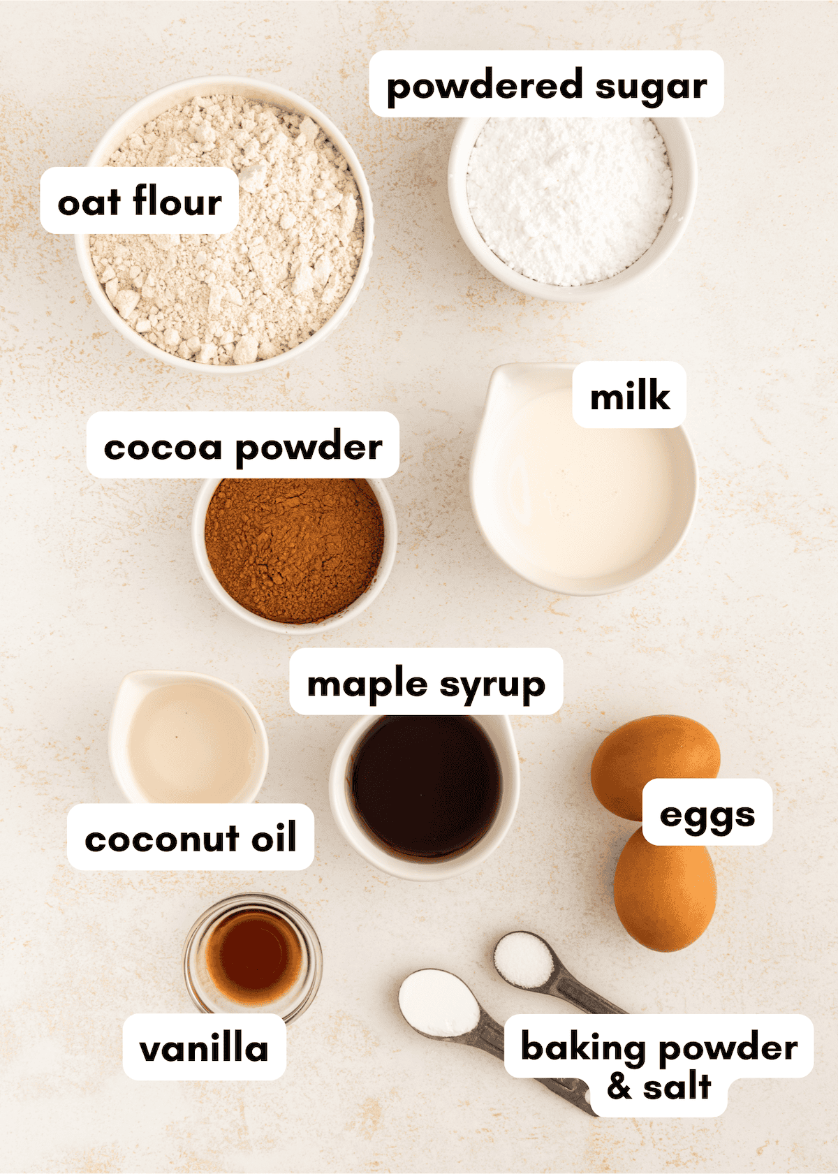 Baking ingredients labeled: oat flour, cocoa, milk, eggs, maple syrup, coconut oil, vanilla, sugar.
